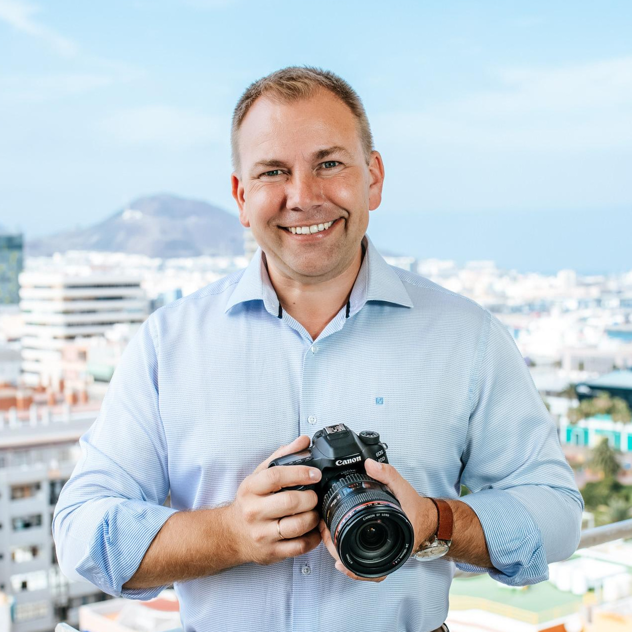 Love Story Photographer Slavik in Gran Canaria A man holding a camera in front of a city.