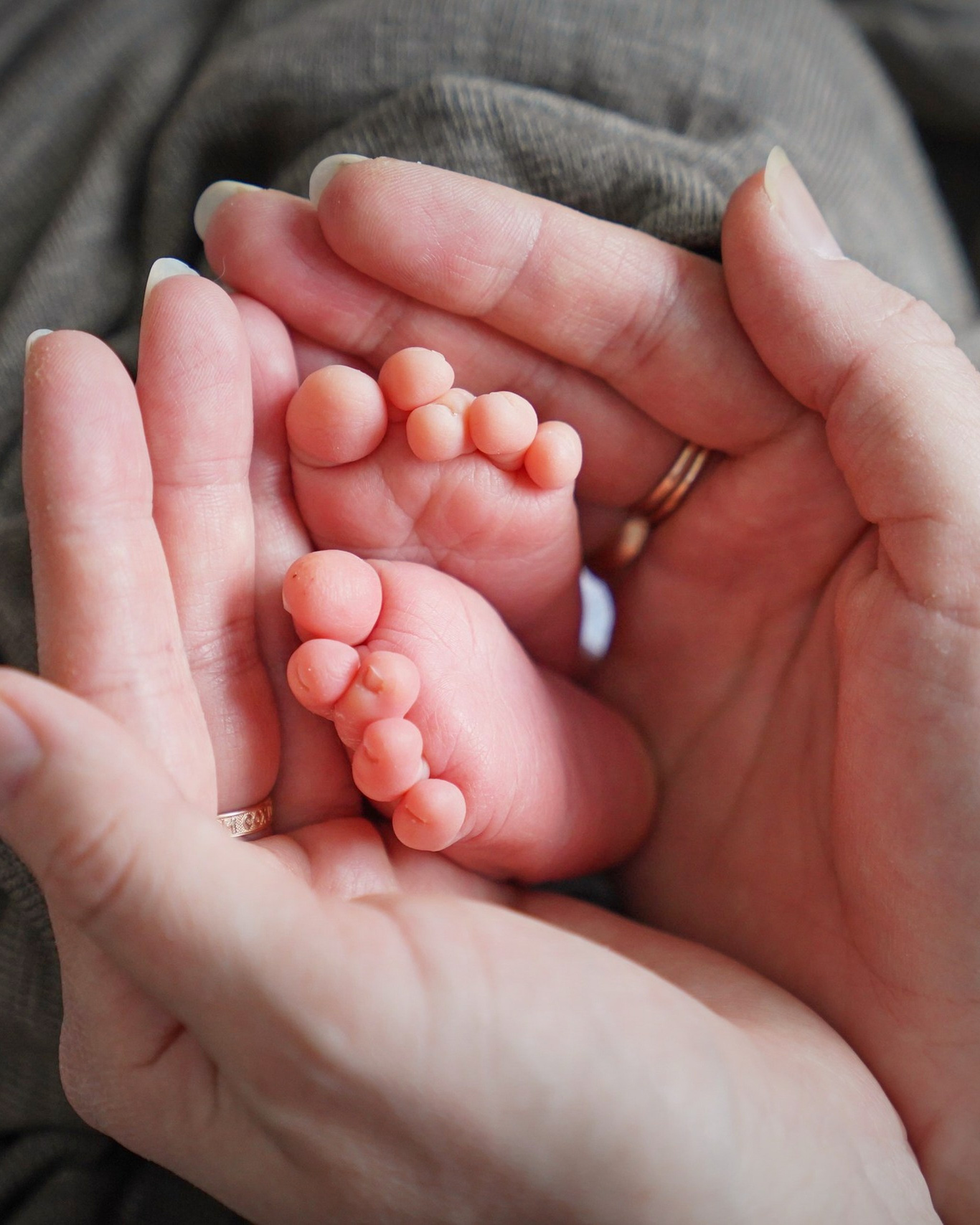 Tiny newborn feet carefully held in mother's palms