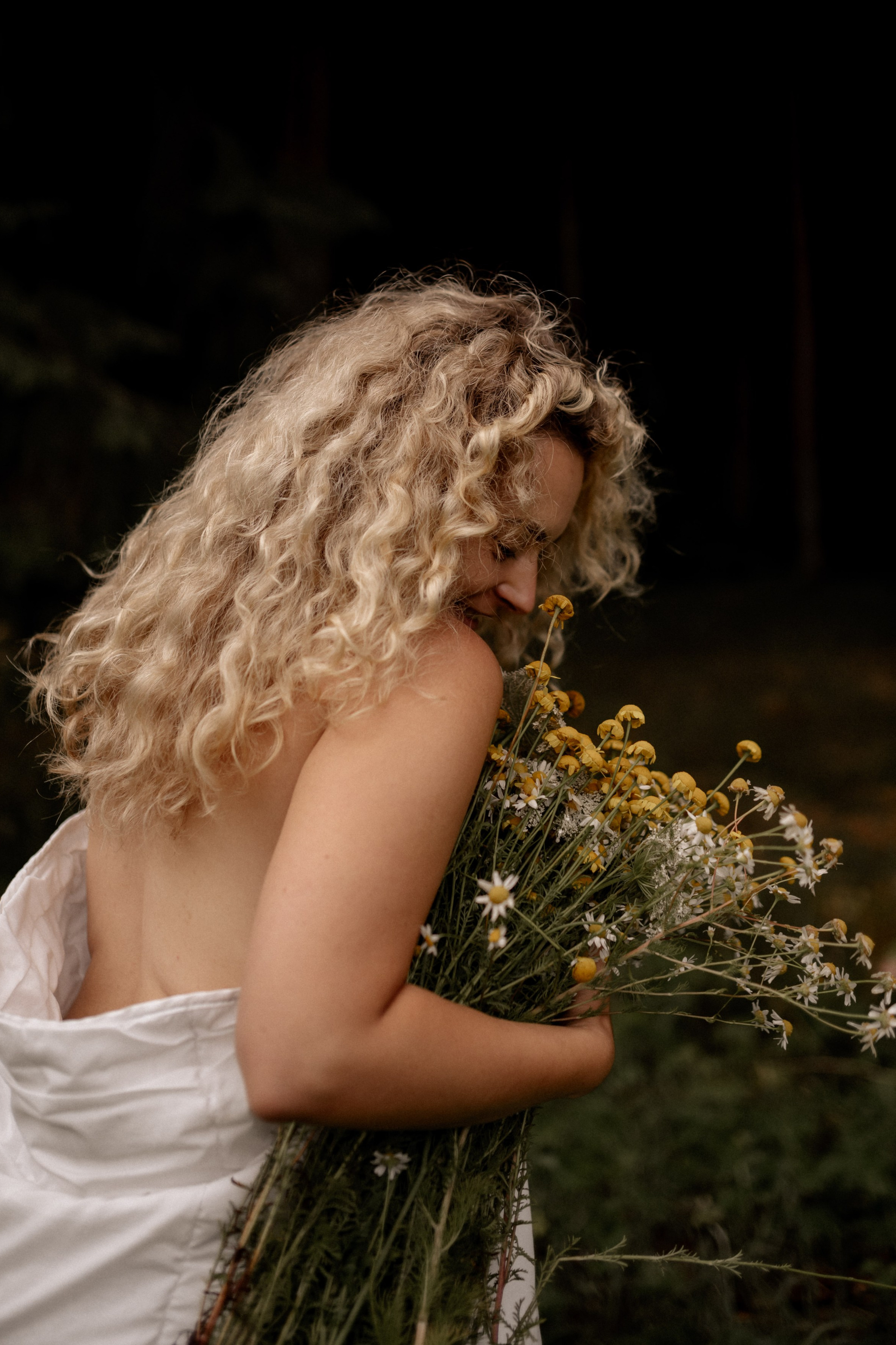 Schöne Frau in eine Decke umwickelt steht mit einem Blumenstrauß im Wald bei Neuendettelsau