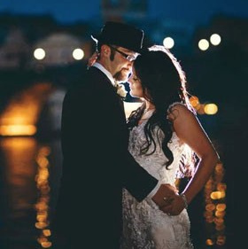 Smiling blonde-haired Swiss bride smiles lovingly towards her Italian groom as he looks towards the camera at a garden in Prague. 