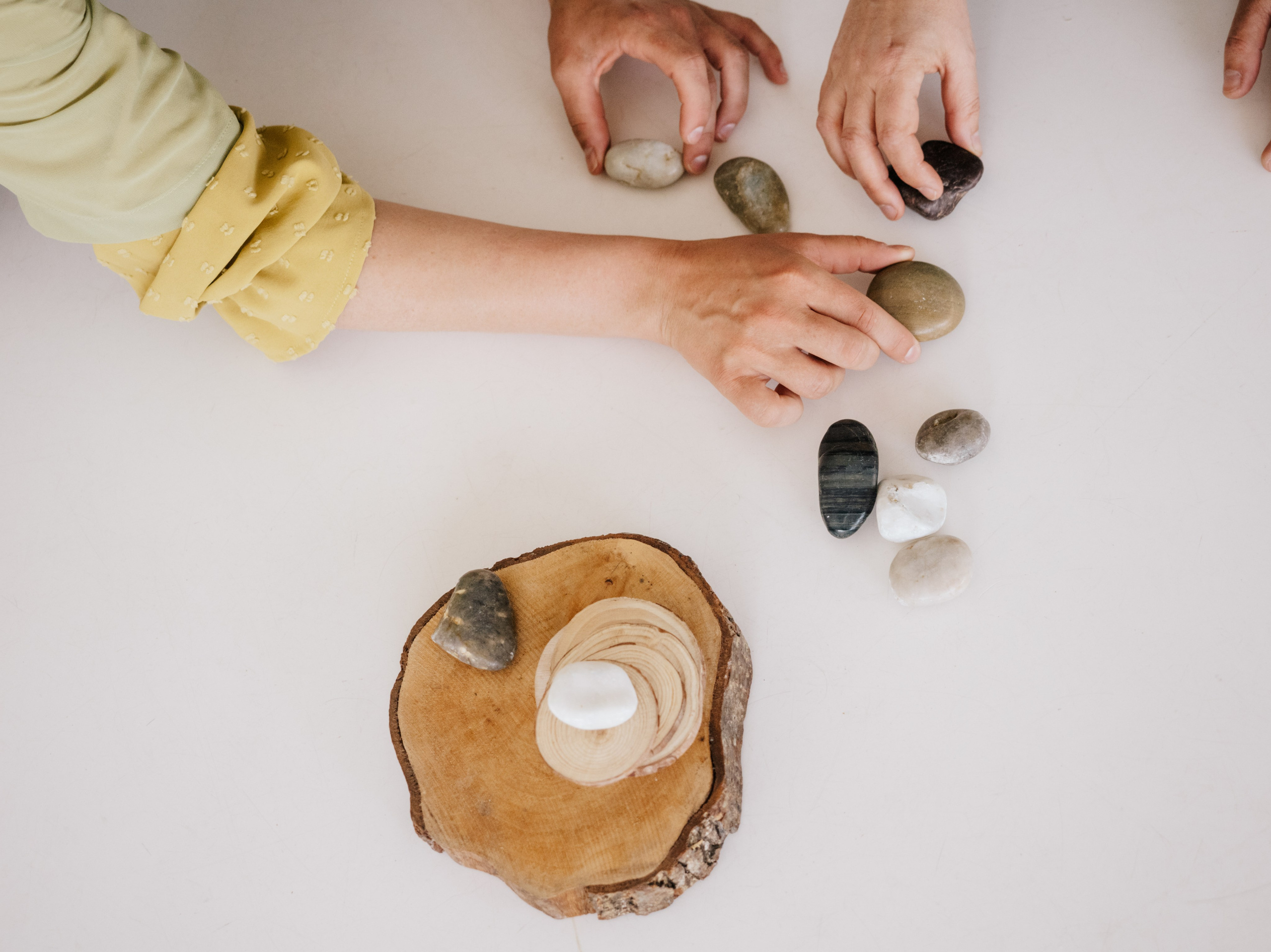Hands placing stones and little wood slices.