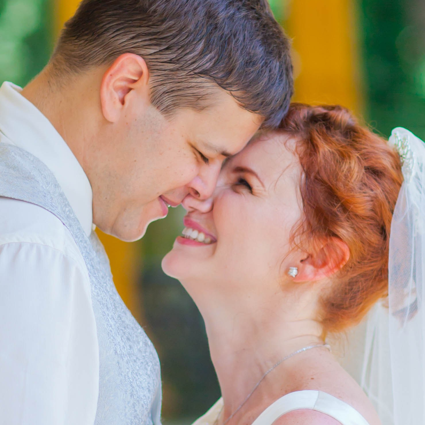 Smiling blonde-haired Swiss bride smiles lovingly towards her Italian groom as he looks towards the camera at a garden in Prague. 