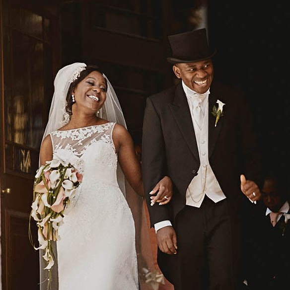 Smiling blonde-haired Swiss bride smiles lovingly towards her Italian groom as he looks towards the camera at a garden in Prague. 