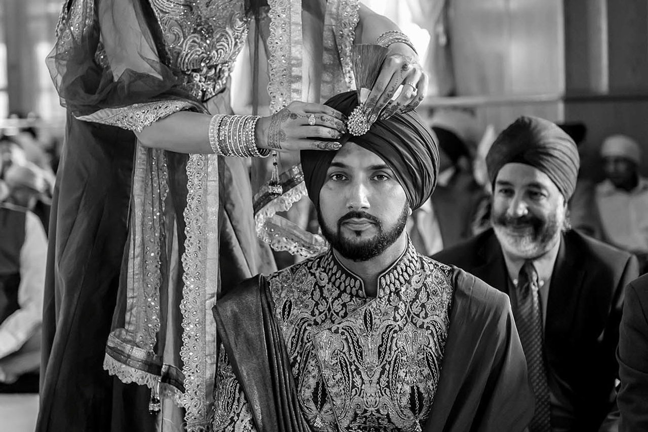 Wedding photographer Guru Nanak Darbar Gurdwara London UK Nikon D850  Groom's sister arranging Sarpech
