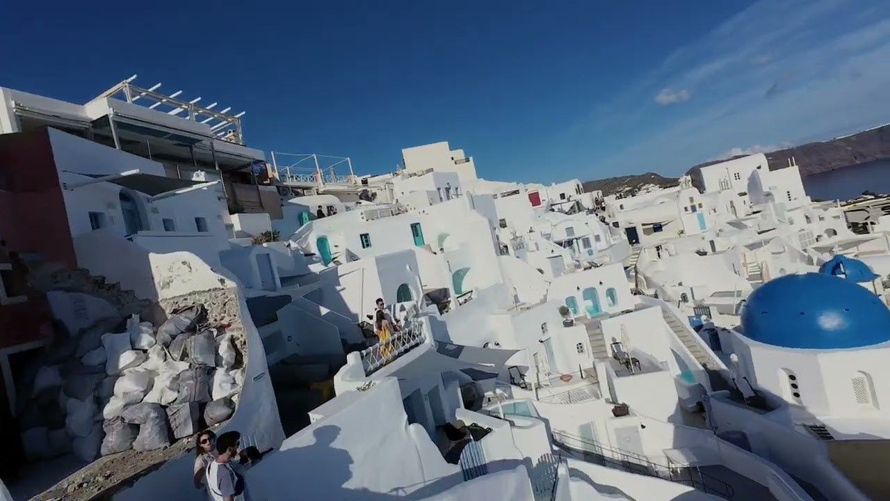 Whispers of Caldera Romance: Japanese Couple’s Enchanted Drone Journey at Mystique Santorini. Photographe vidéaste à Santorin|Séances photos de Robe volante Santorin|