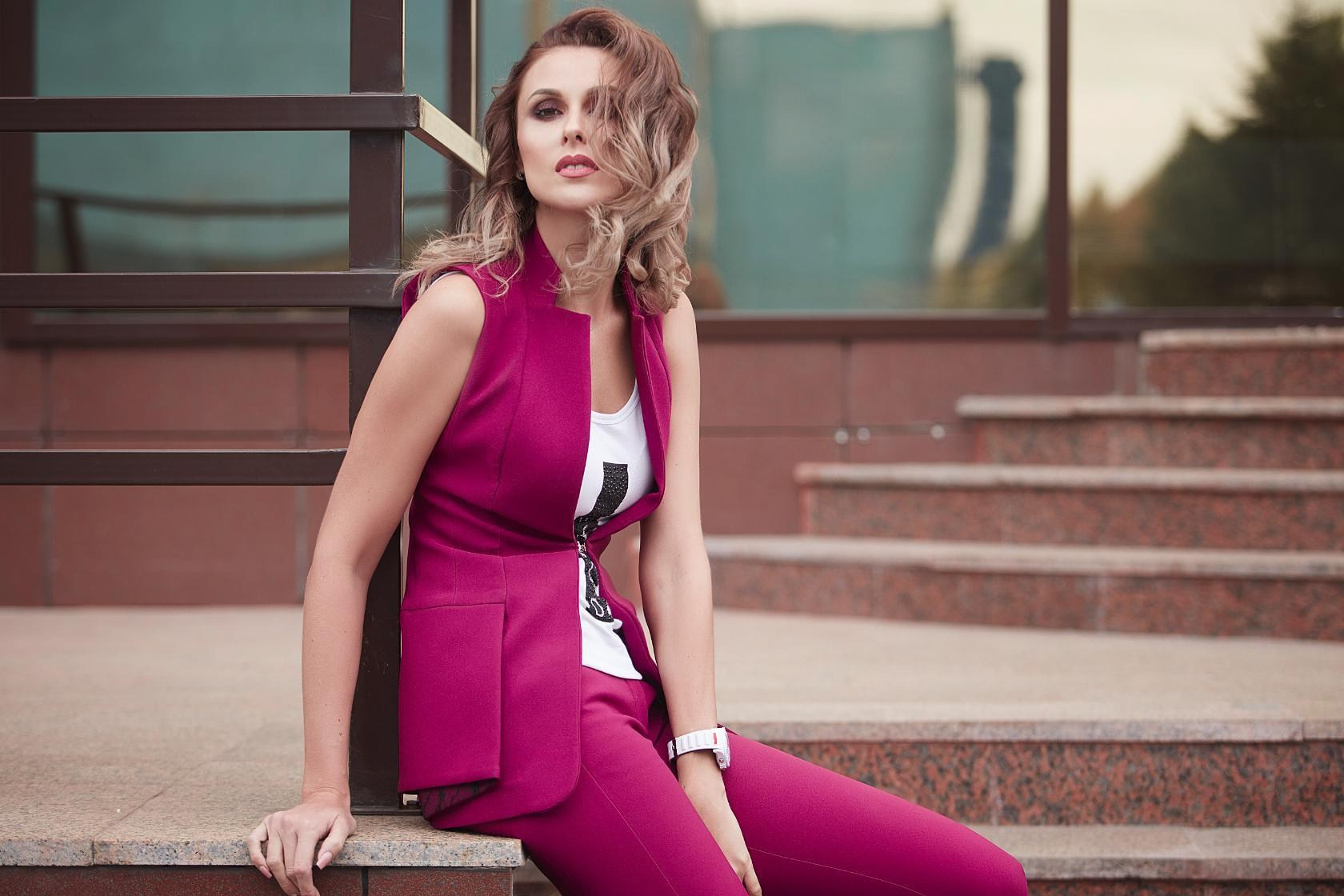 Femme d’affaires souriante en tailleur rose fuchsia assise sur les marches – séance photo corporate en extérieur en France