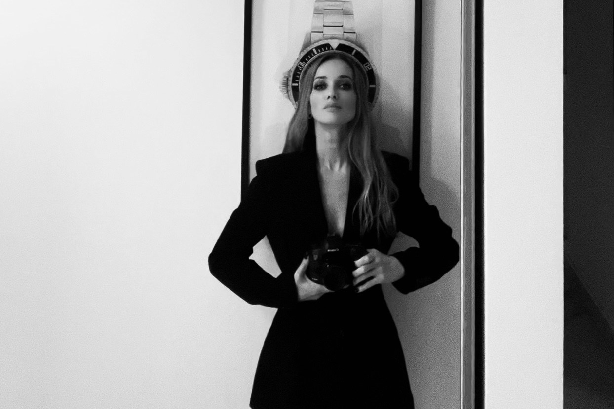 Portrait artistique en noir et blanc d’une femme debout devant un mur décoré – ambiance mystérieuse et contemporaine