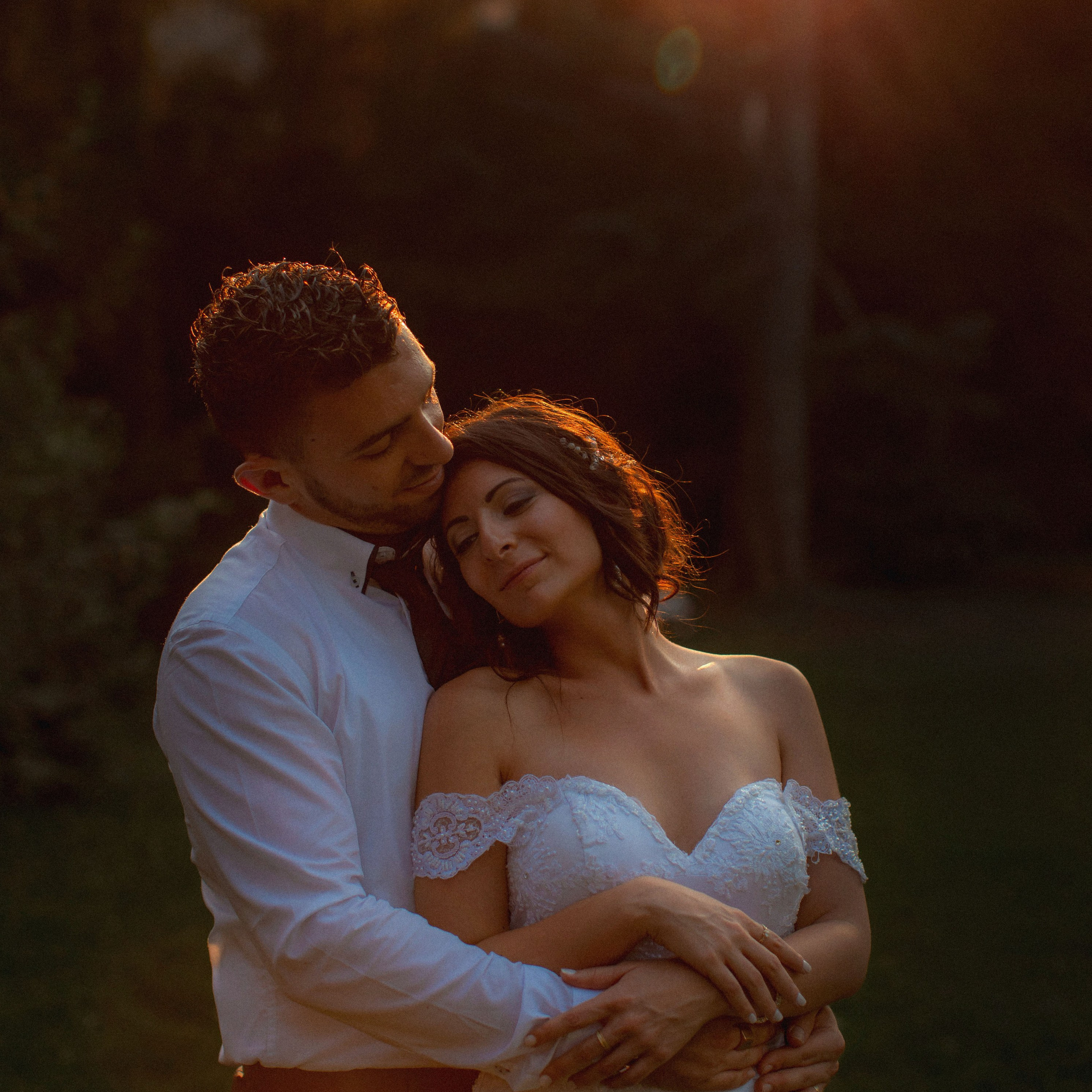 Smiling blonde-haired Swiss bride smiles lovingly towards her Italian groom as he looks towards the camera at a garden in Prague. 