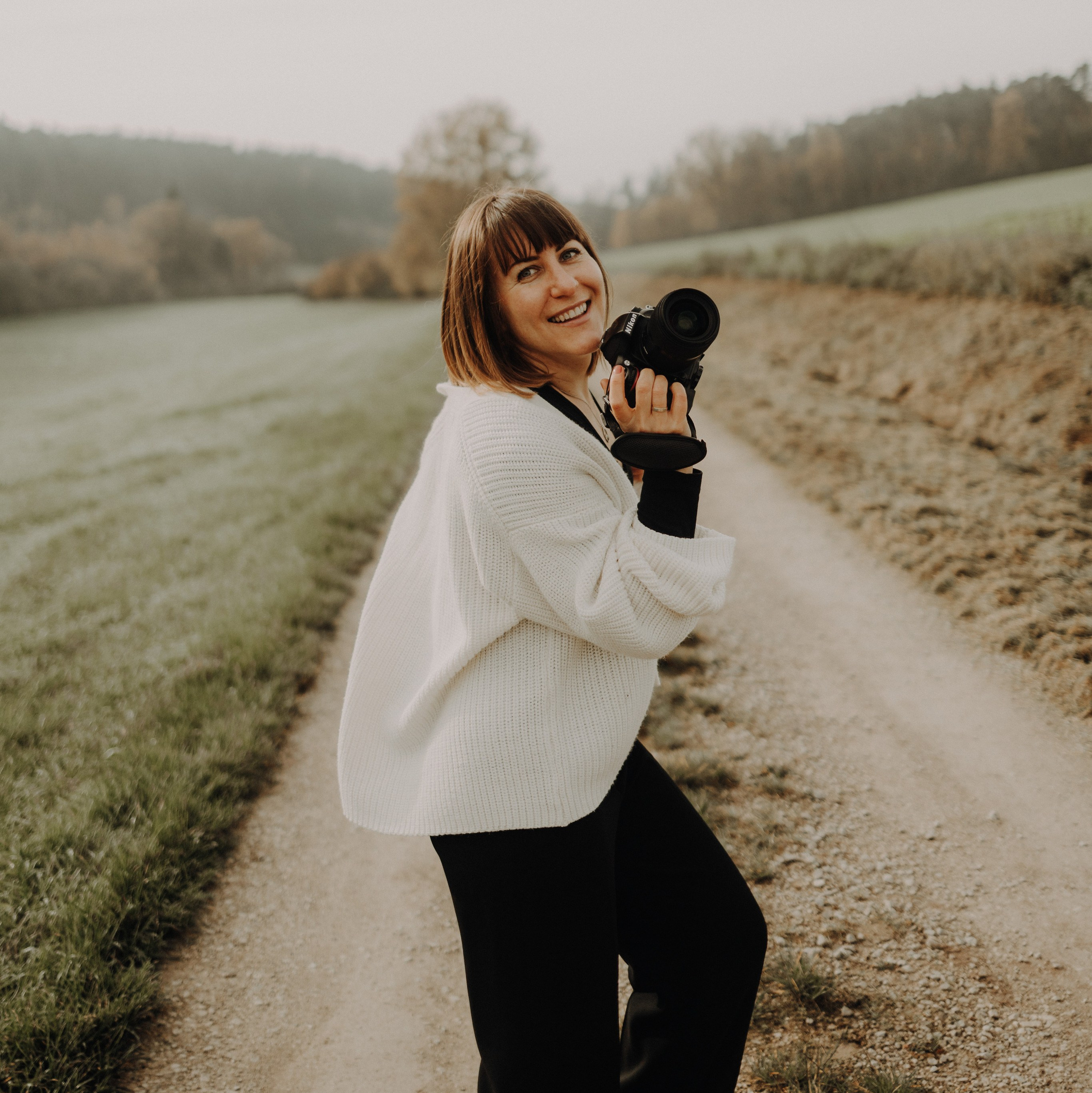 Fotografin aus Ansbach lacht mit einer Kamera in der Hand