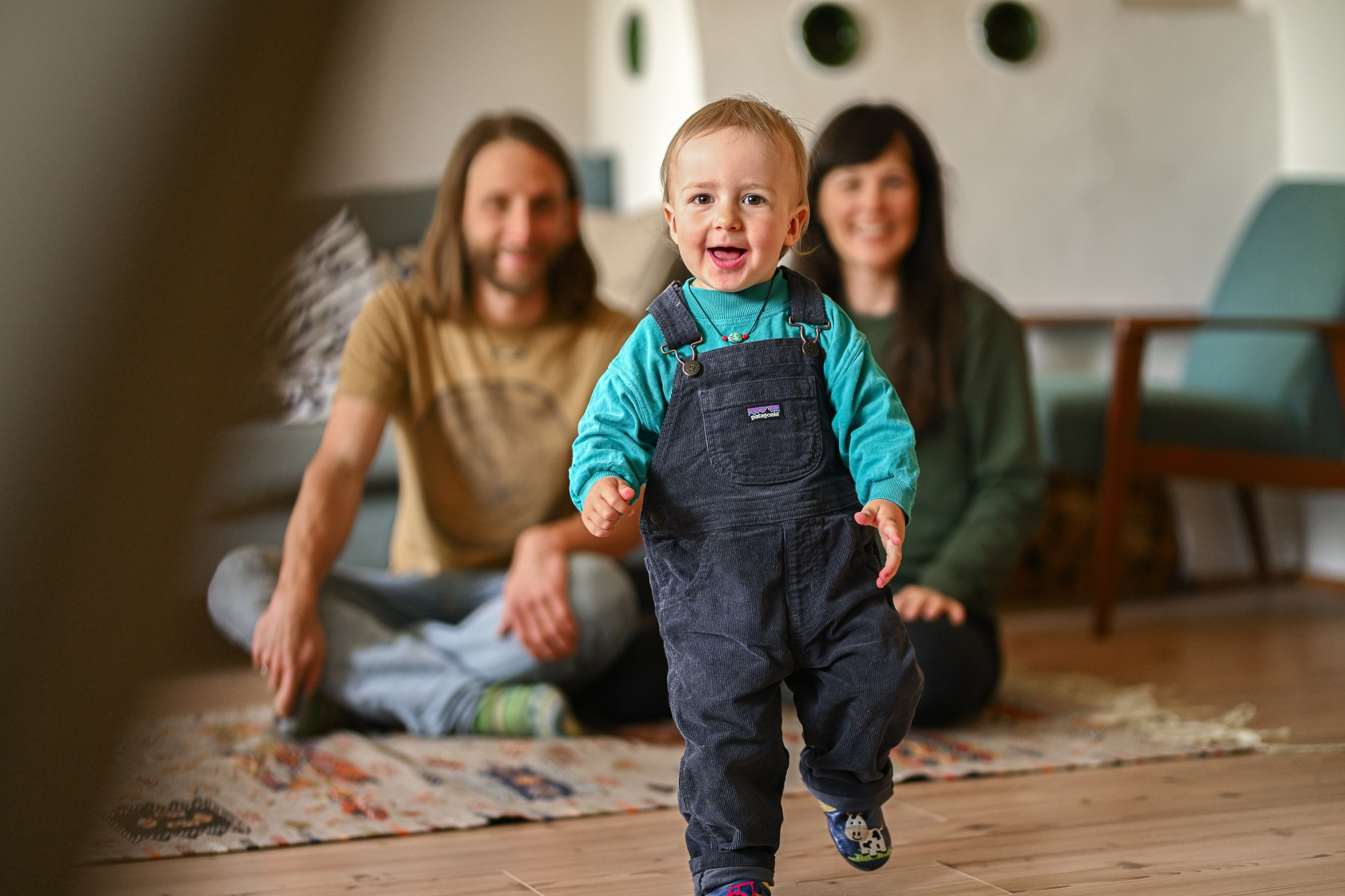Familienfoto - kleiner Junge rennt vor lächelnden Eltern davon