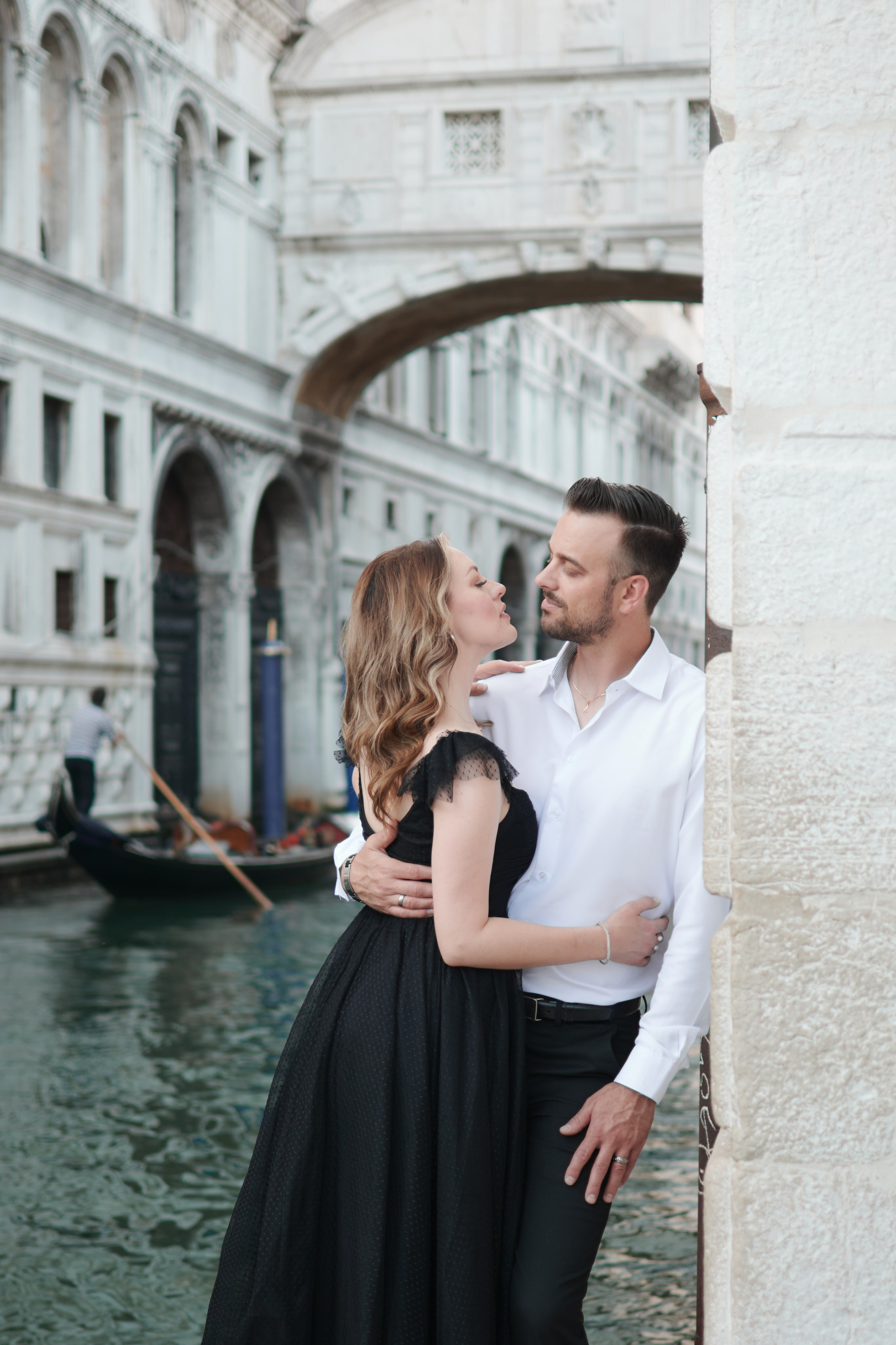 A stunning young woman in a red dress stands in San Marco Square, Venice, with the historic Arca di San Marco in the background. The architectural details of the Arca and the surrounding buildings add to the romantic atmosphere of the scene. The woman's dress drapes elegantly around her figure, adding to the captivating allure of the photo. The contrast between the dark dress and the warm colors of the surrounding buildings adds to the overall visual impact of the image, creating a sense of mystery and intrigue. ballerina