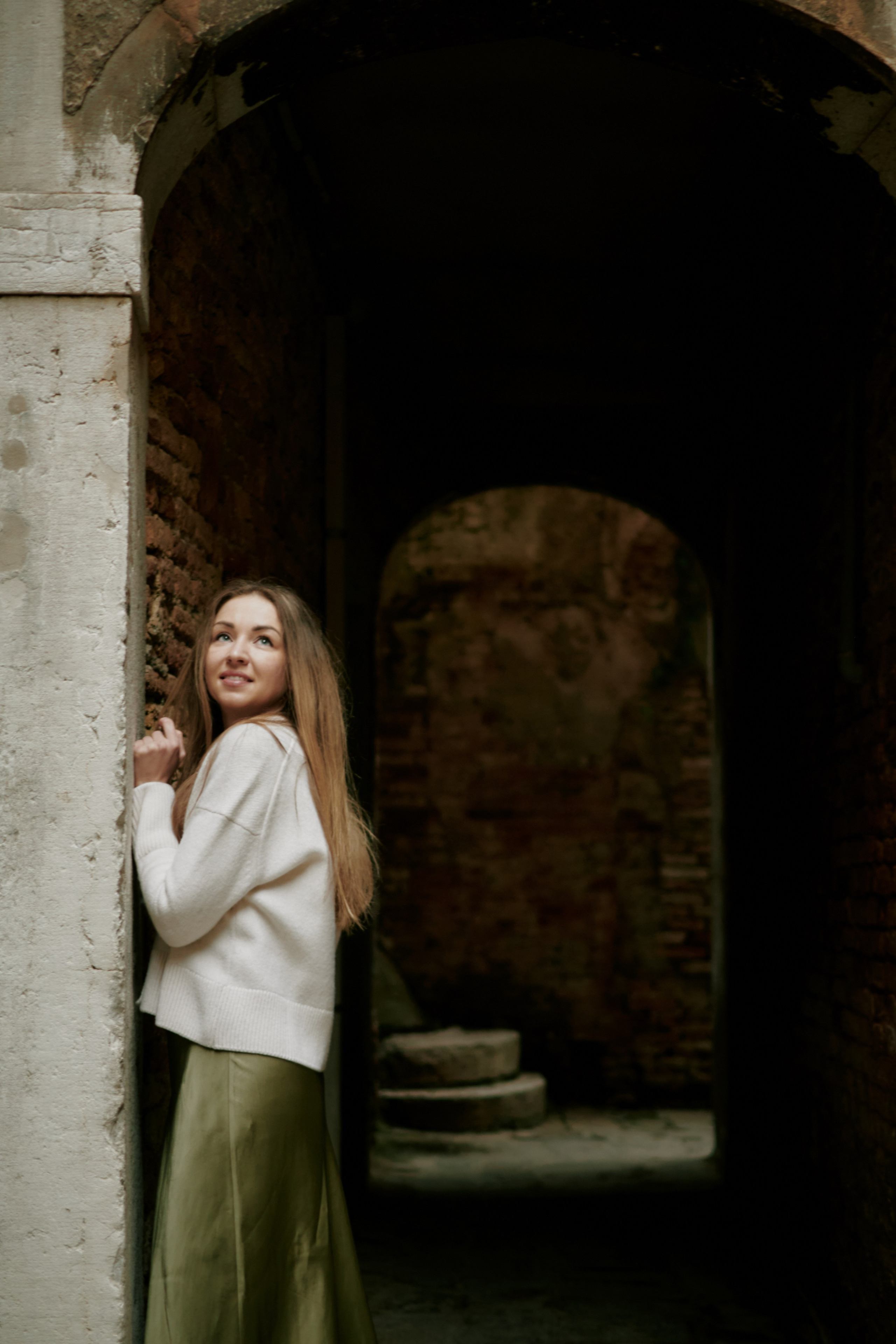 A photographer in Venice, Italy taking portrait photos of carnivel mask Clawn. The carnival mask is standing in front of a beautiful bridge with the iconic canals of Venice in the background. The photographer is crouching down with a camera in hand, capturing Clawn's pose and expression.