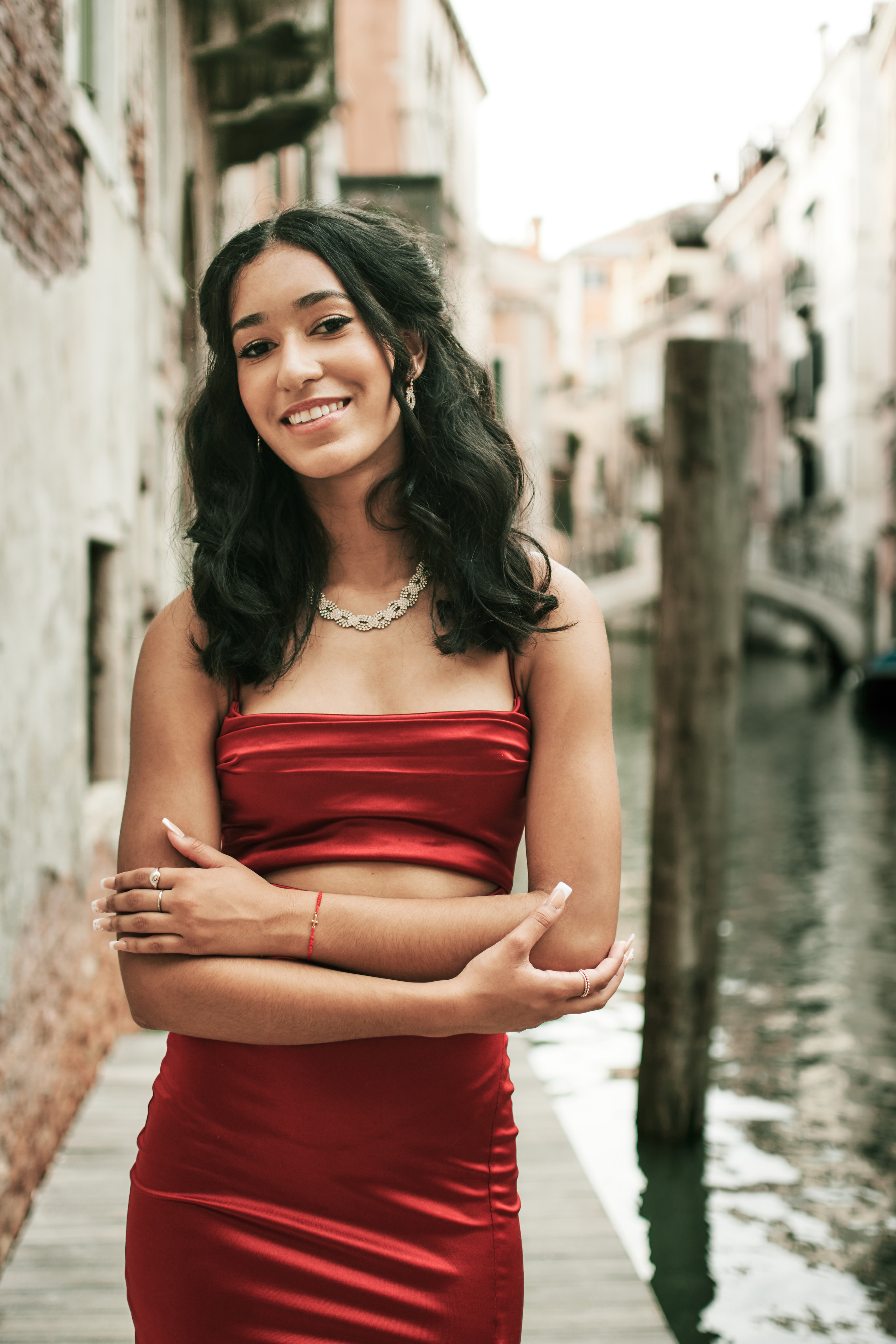 Elegantly dressed girl in red explores the romantic narrows canals of Venice.