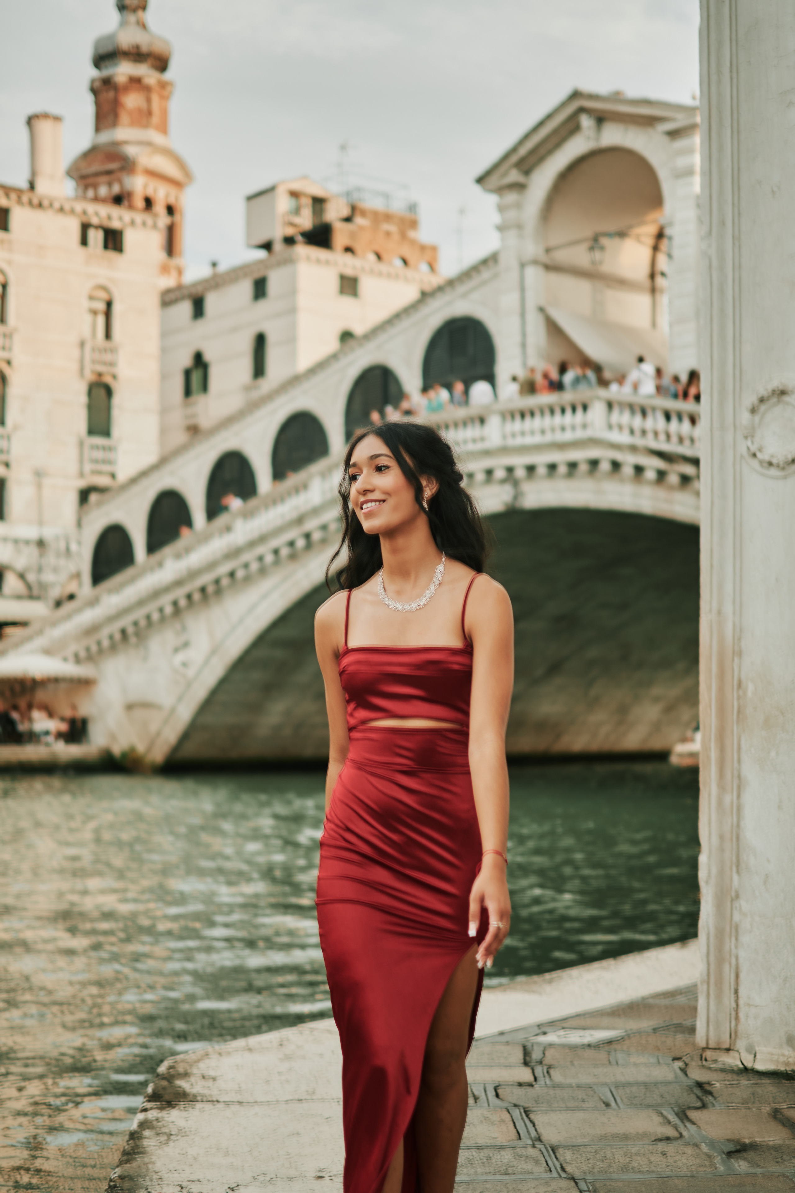 Captivating photoshoot of a young lady in a stunning red dress amidst Venice's charming narrow canals.