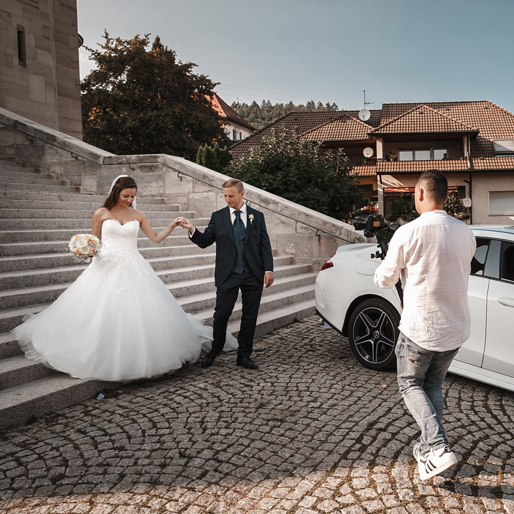 Braut und Bräutigam auf Kopfsteinpflaster vor stilvollem Auto – elegante Hochzeitsbilder in Karlsruhe