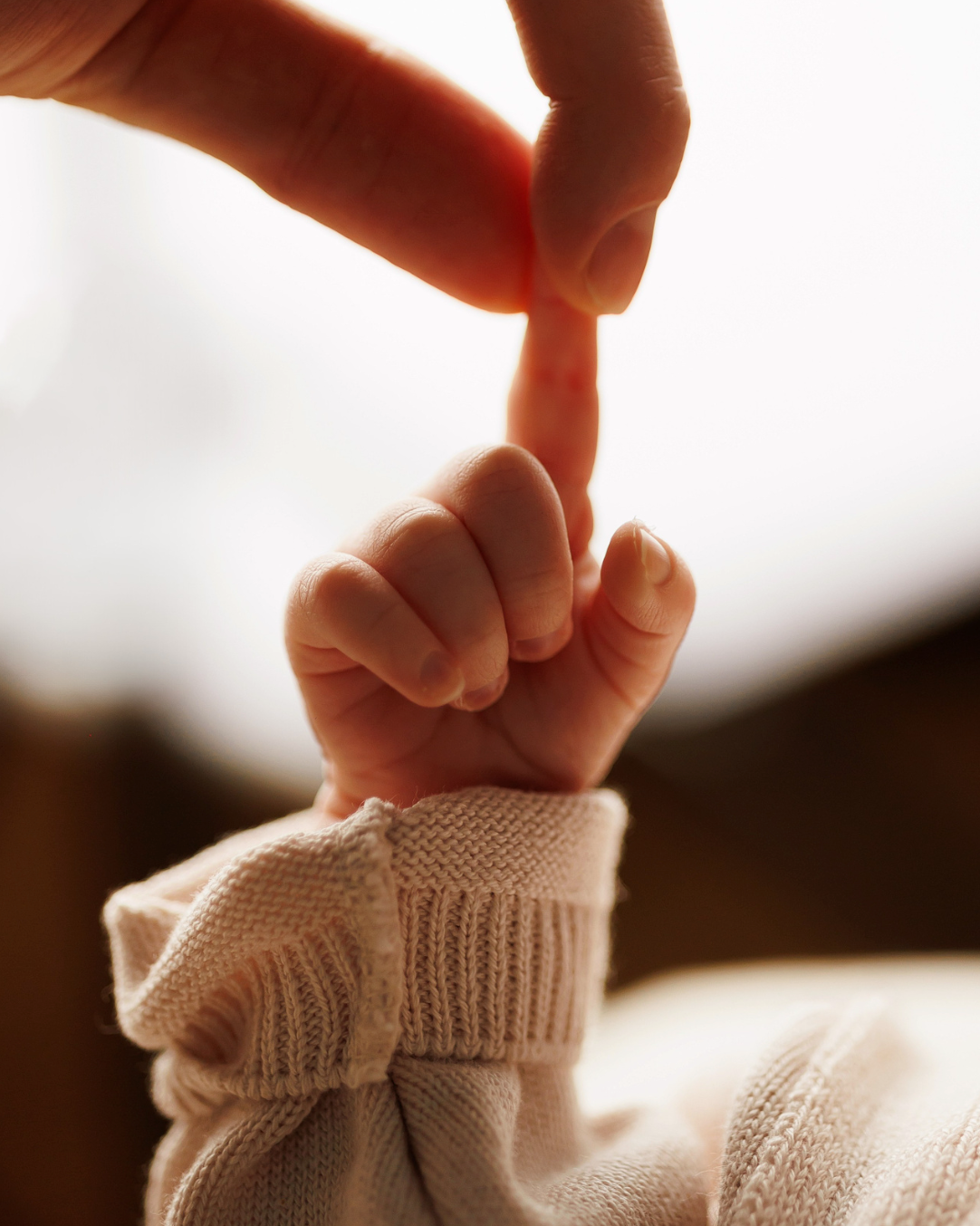 Mother gently holding her newborn's tiny finger with care