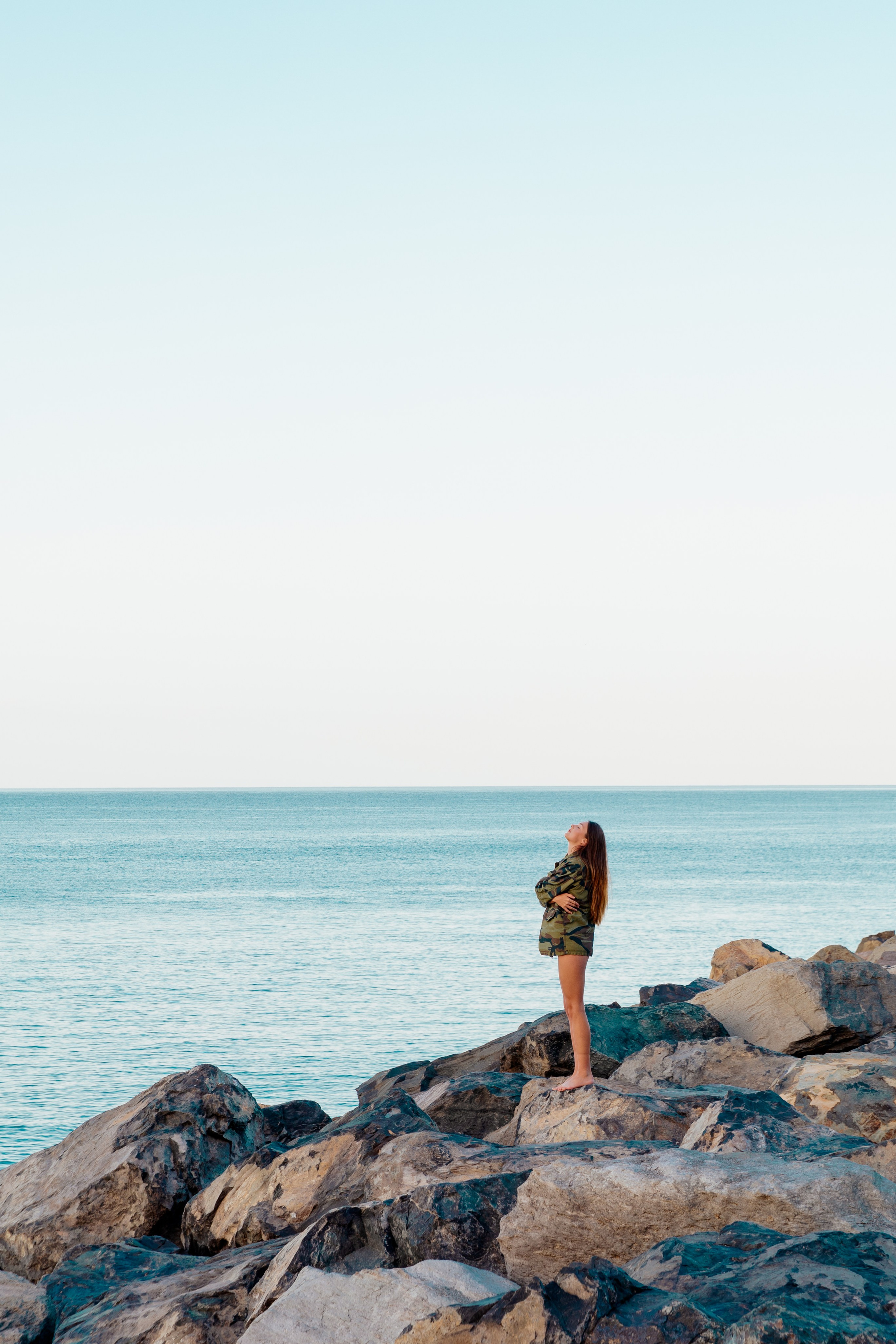 Dreamy girl staying on the sones and looking at the sea