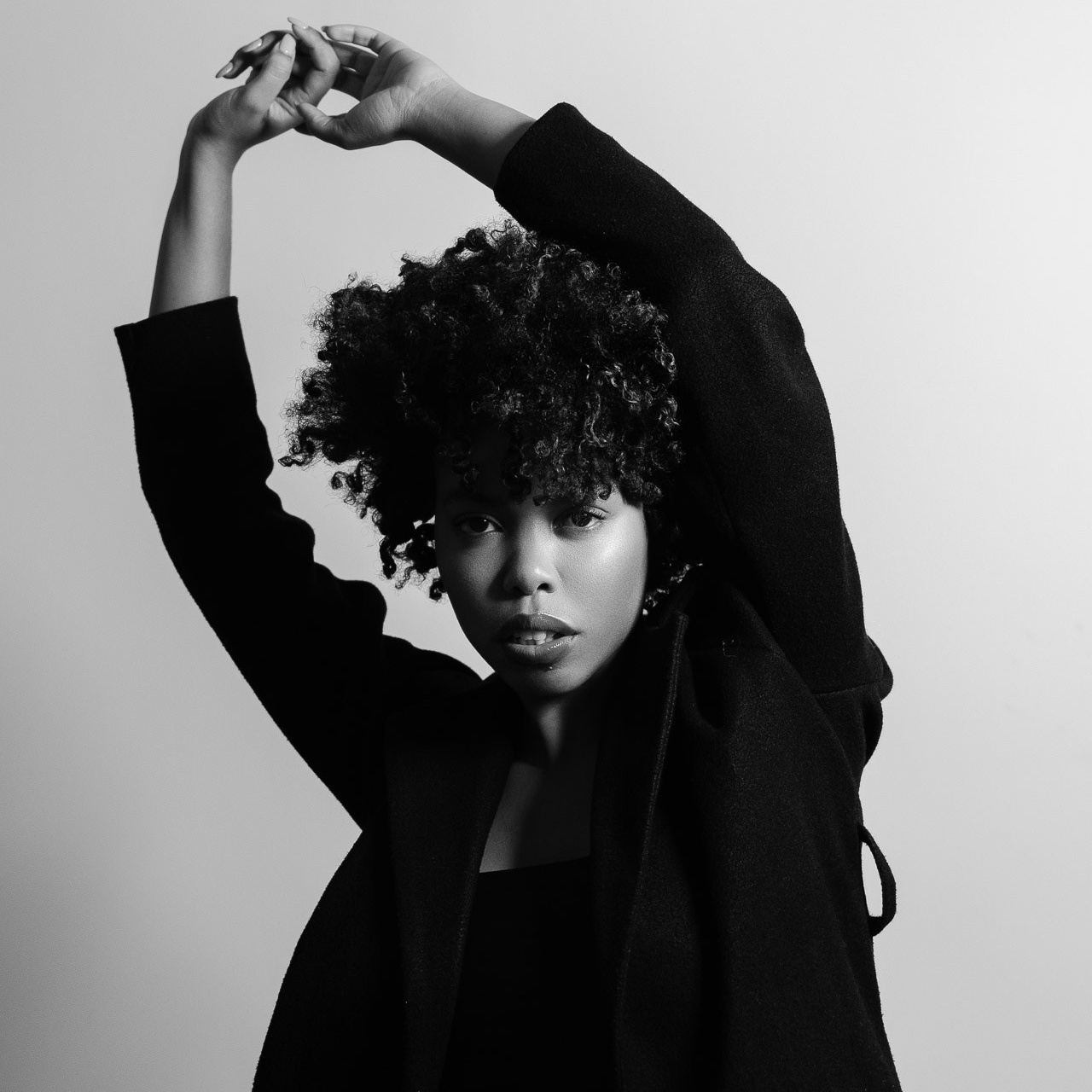 Black-and-white portrait of female model with arms raised