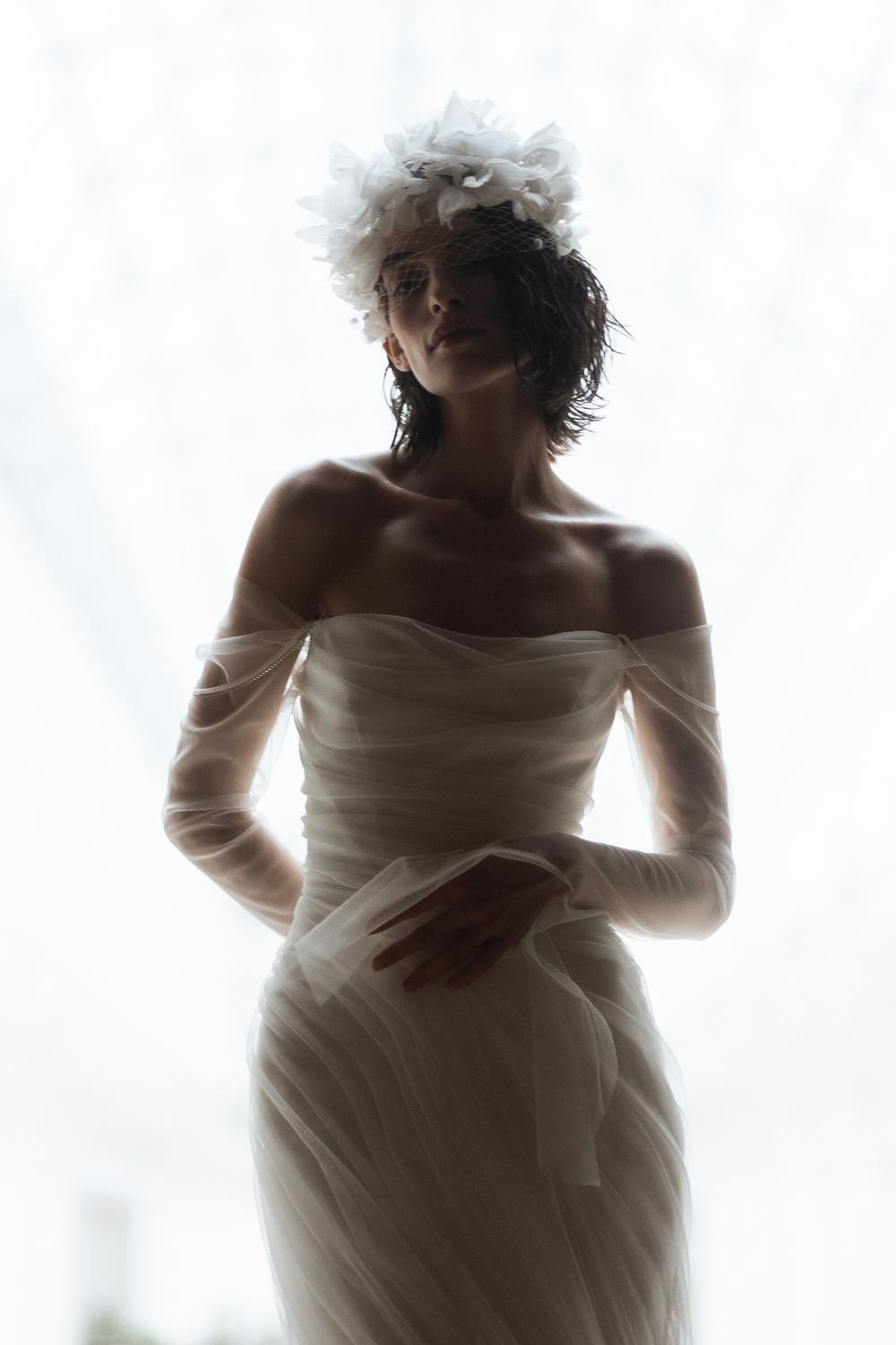 Bride in minimalist gown posing against architectural backdrop