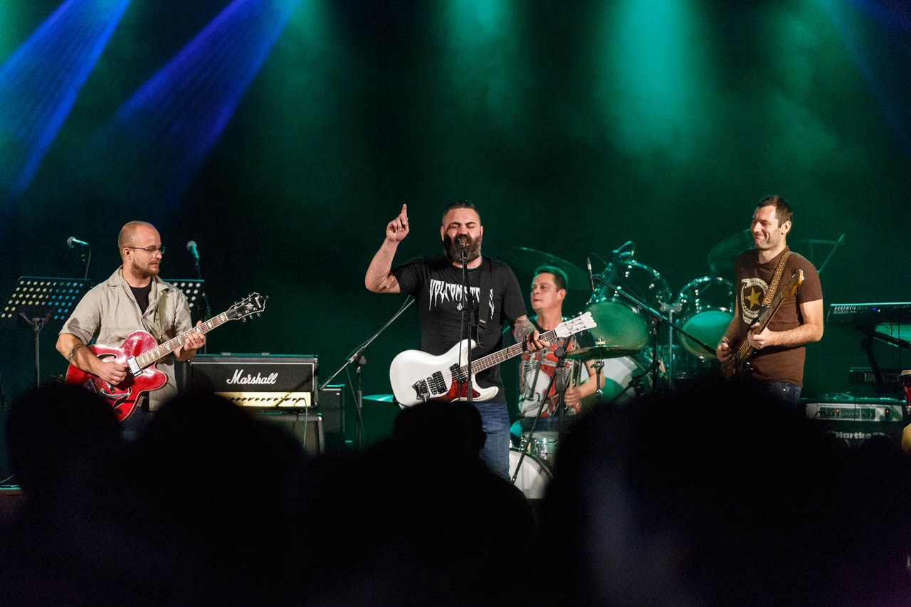 Članovi benda Moonshine Alligators na sceni dok publika uživa u koncertnoj atmosferi.