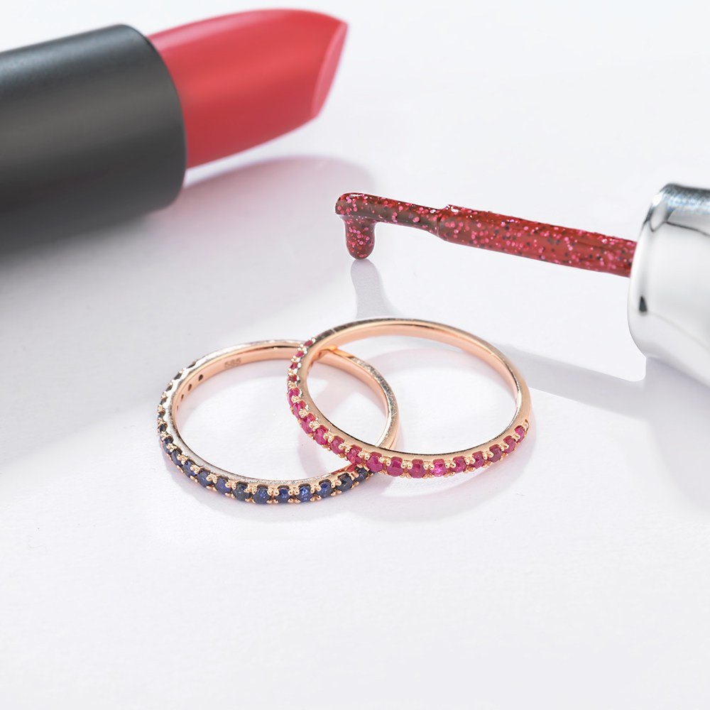 Dva zlatna prstena na belom stolu sa karminom i lak za nokte.