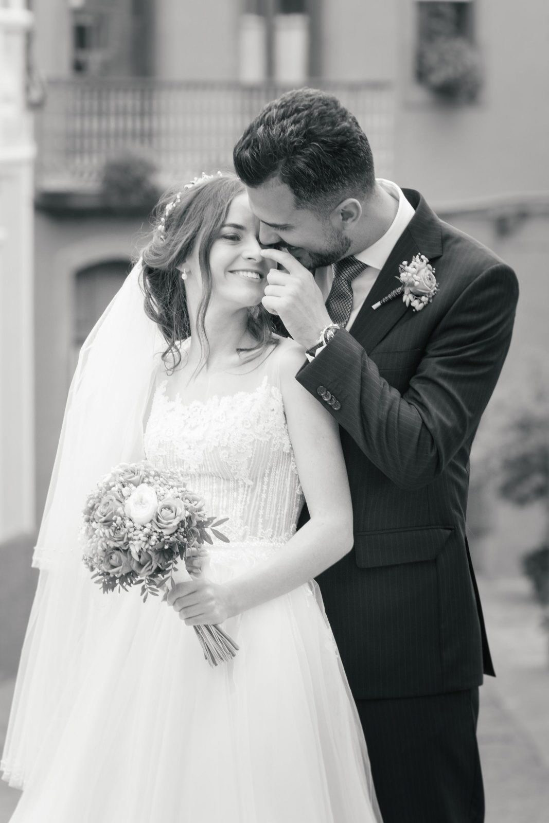 A bride and groom are kissing in front of a building.