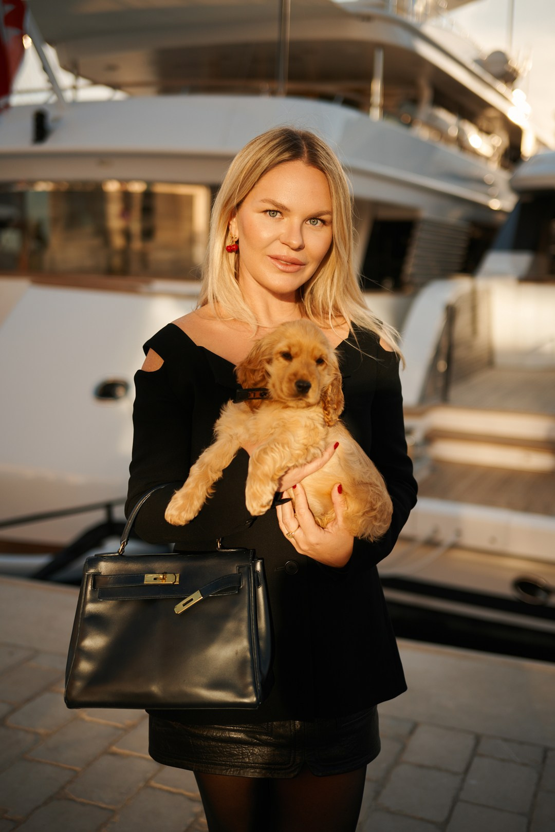 Loving mother holding small dog with marina and yachts in Cannes background