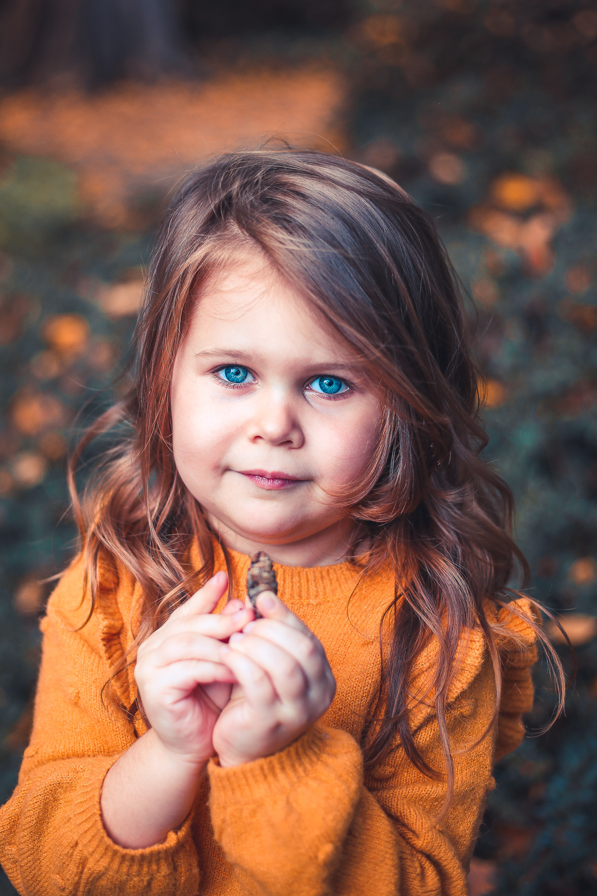 Kleines Mädchen mit blauen Augen im orangenen Pullover im Park