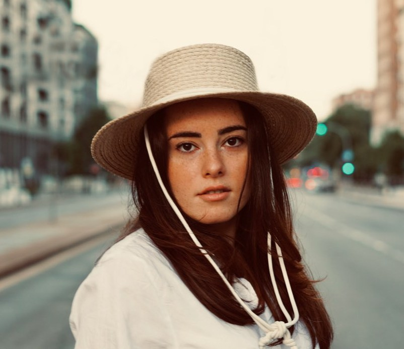 Donna con il cappello davanti alla Stazione Centrale di Milano illuminata dalla luce del mattino.