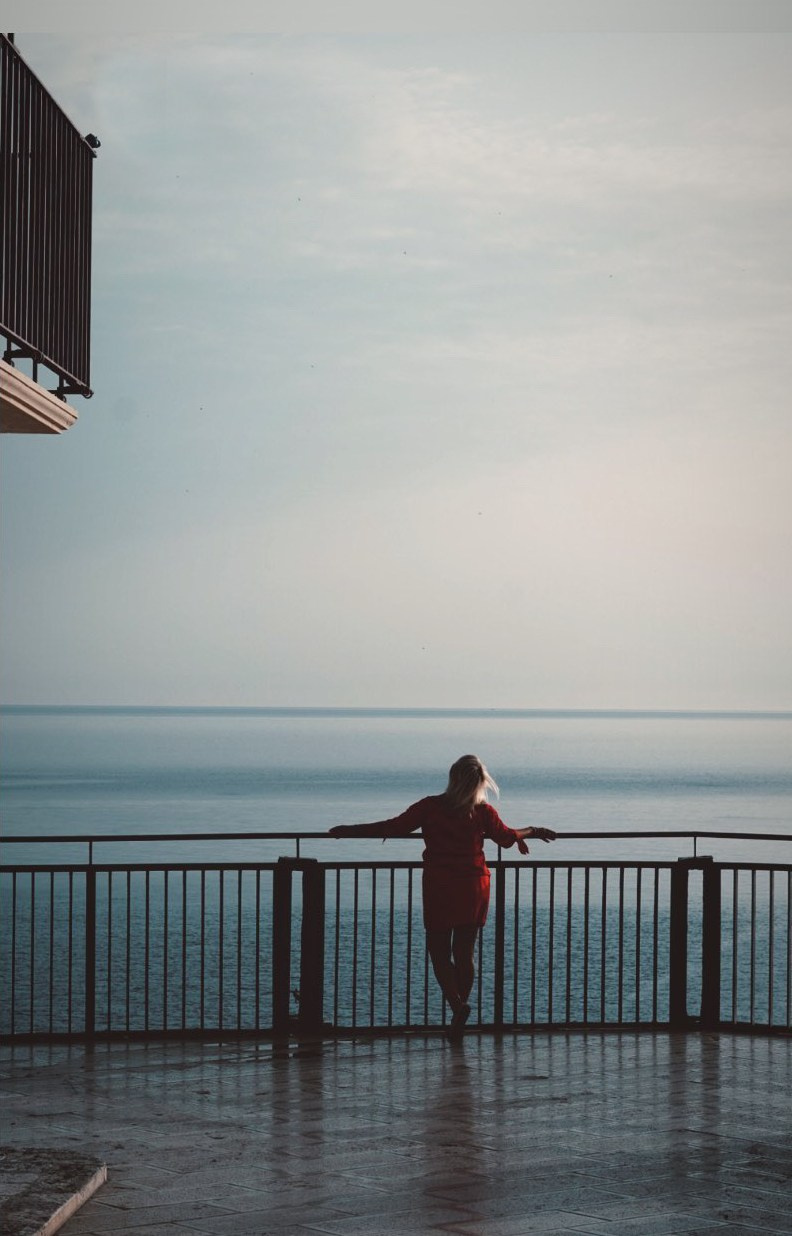 Bella donna che accoglie l’alba a Polignano a Mare, godendosi i raggi caldi del sole.