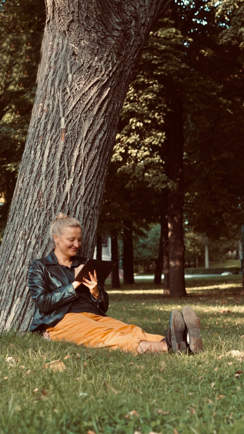 Donna graphic designer che disegna il suo lavoro in un parco all’aperto.