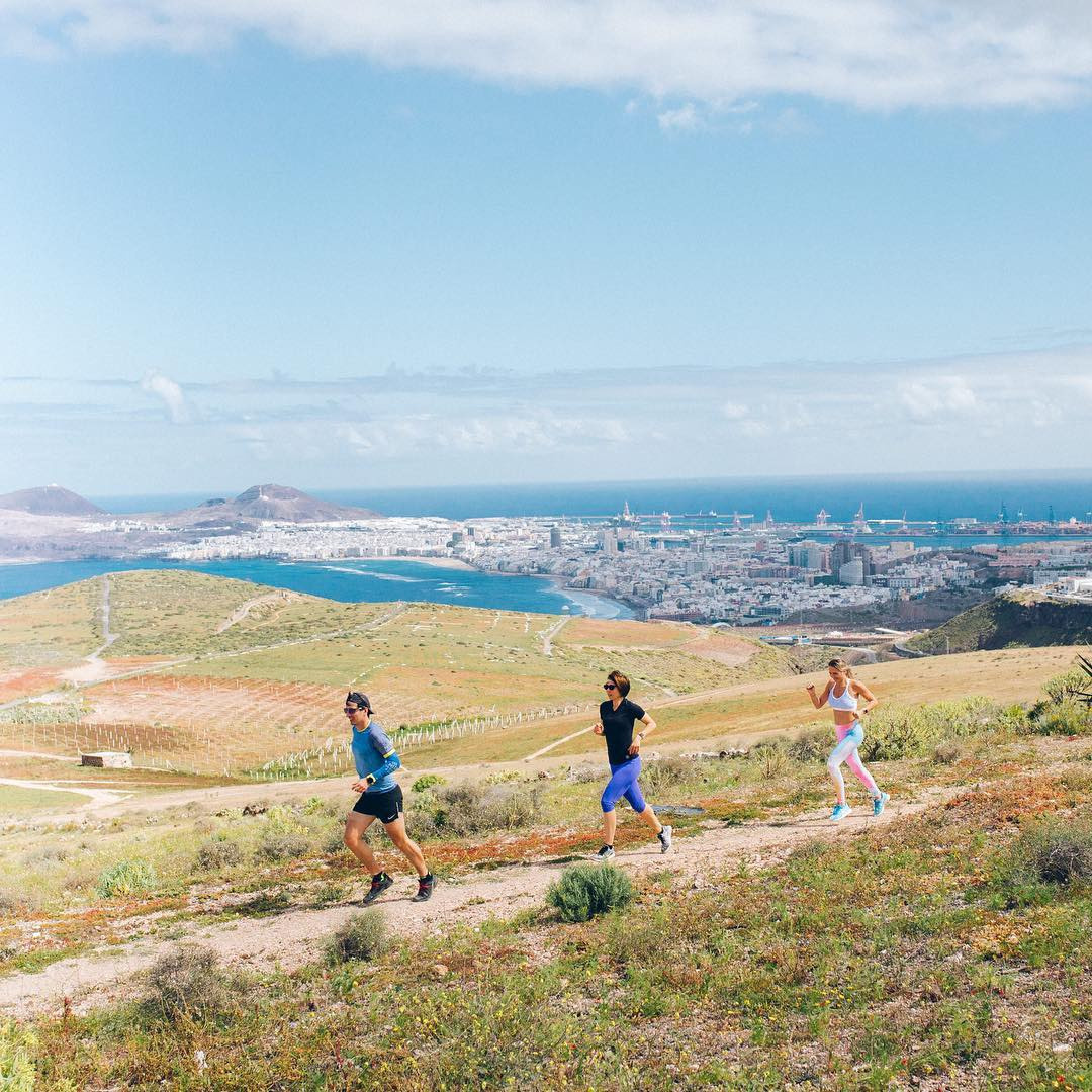 A group of people running on a hill with a view of the ocean.