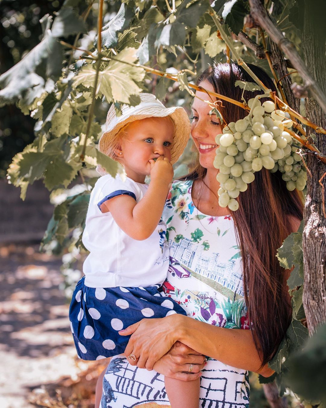 Une femme et un enfant tiennent des raisins dans un vignoble.