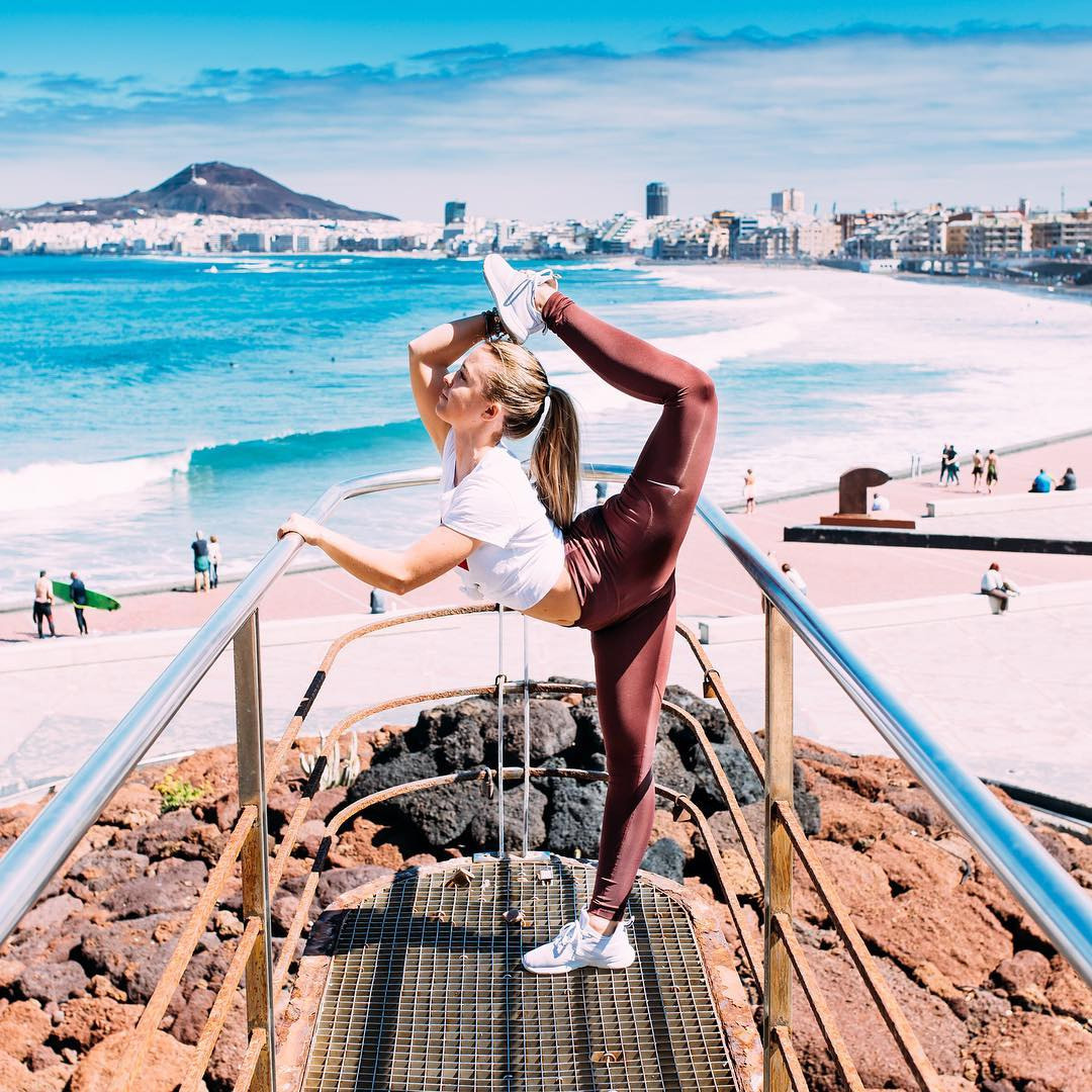 A woman doing yoga on a railing near the ocean.