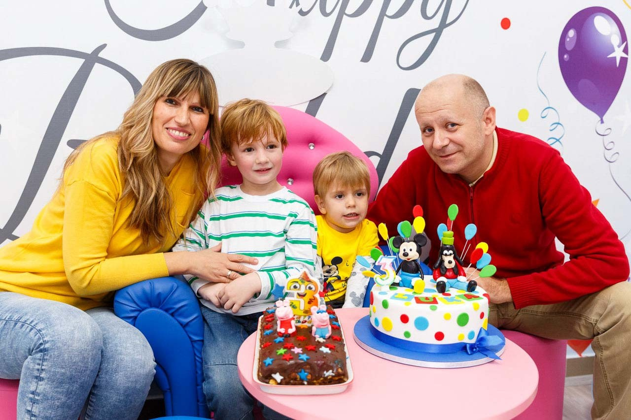Slavljenik sa porodicom u šarenom okruženju rođendanske proslave. Porodični portret sa slavljenikom.