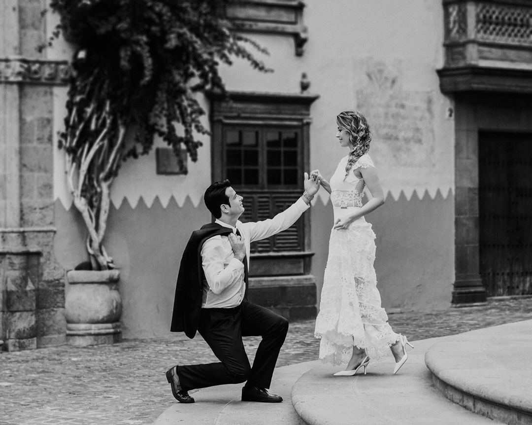 A bride and groom kneeling on steps in front of a building.