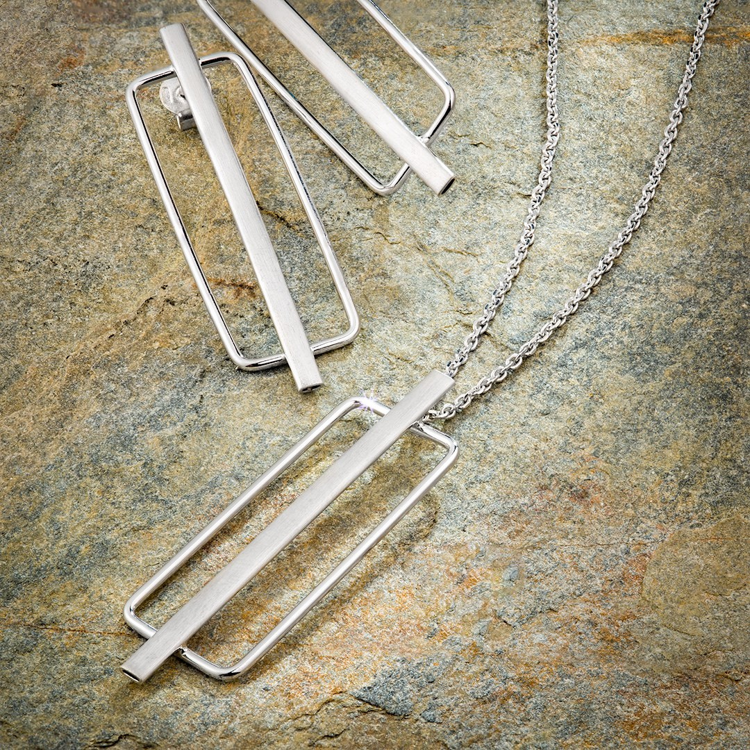 Ogrlica i menjdjuse položeni na zelenom kamenu.