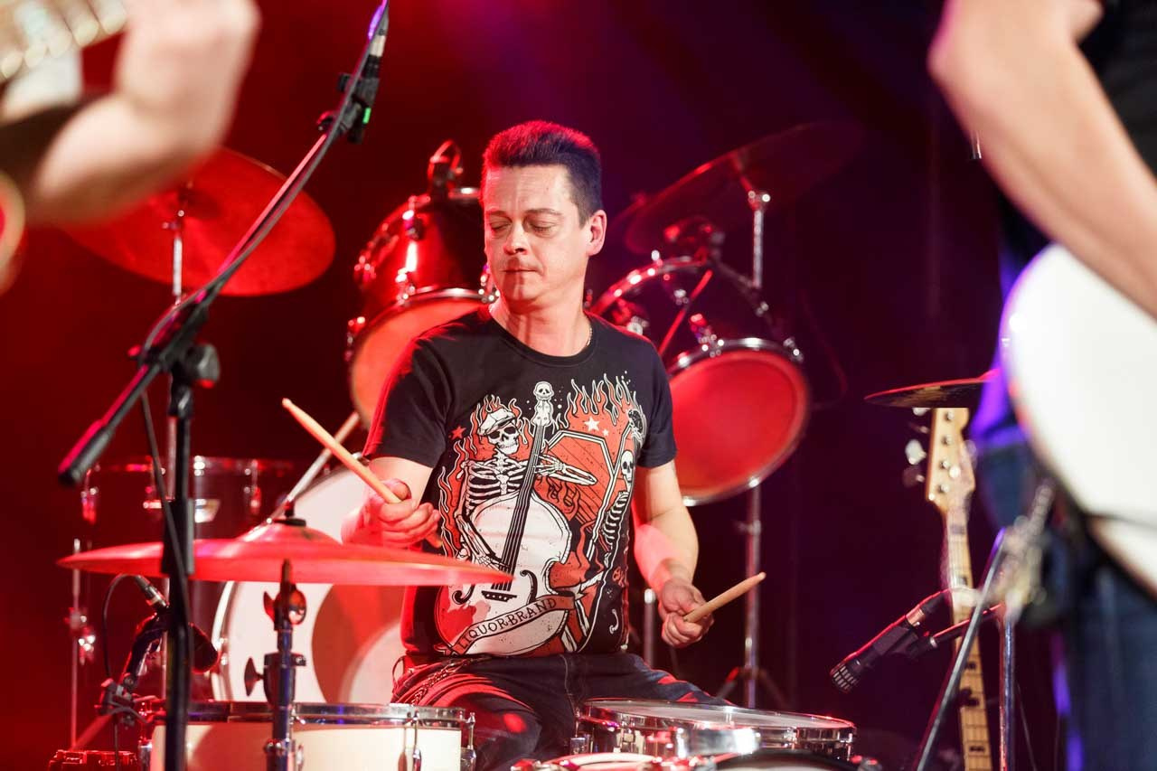 Bubnjar Moonshine Alligators benda u dinamičnom nastupu, okružen bubnjevima i reflektorima na sceni.