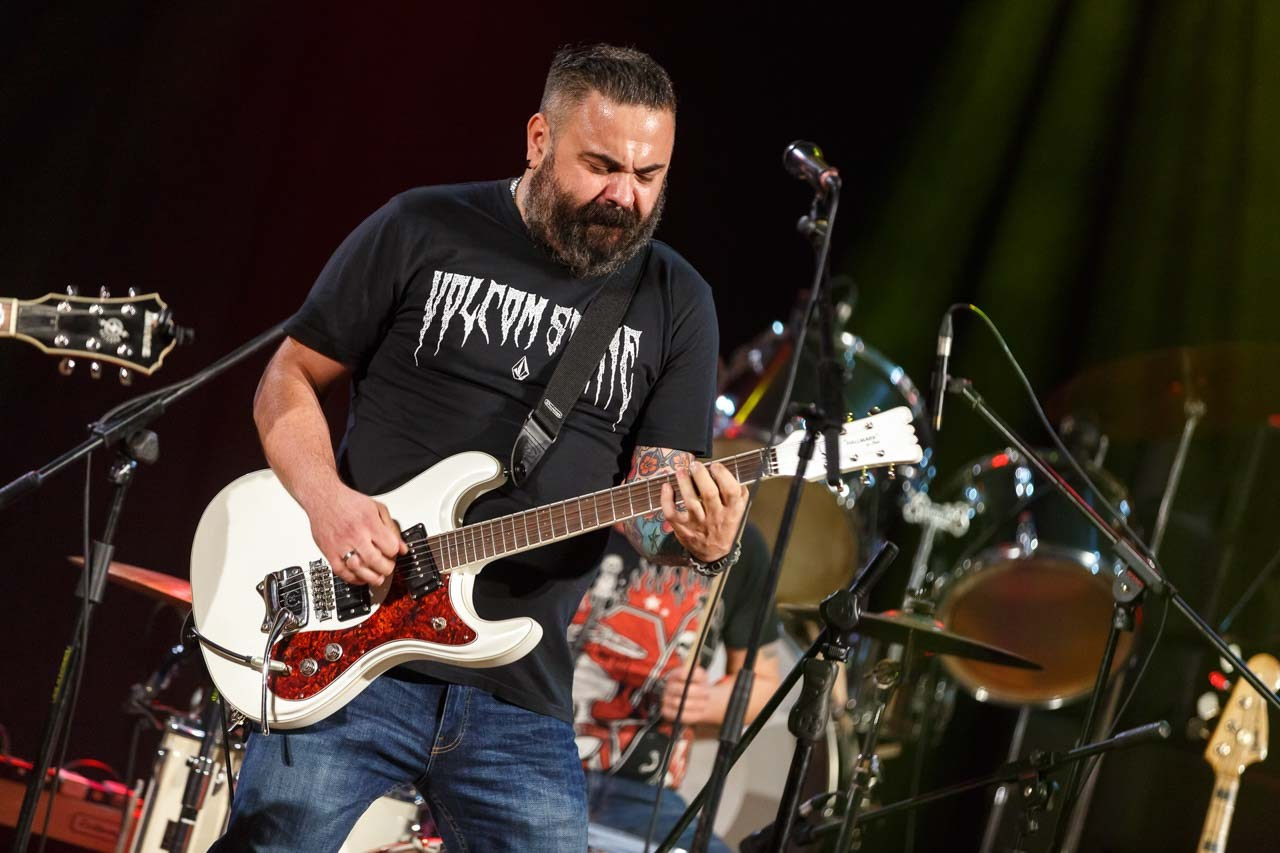 Pevač i gitarista Moonshine Alligators benda u prvom planu sa izražajnim nastupom tokom koncerta.