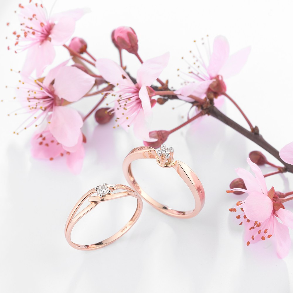 Dva zlatna prstena pored grančice sa cvećem.