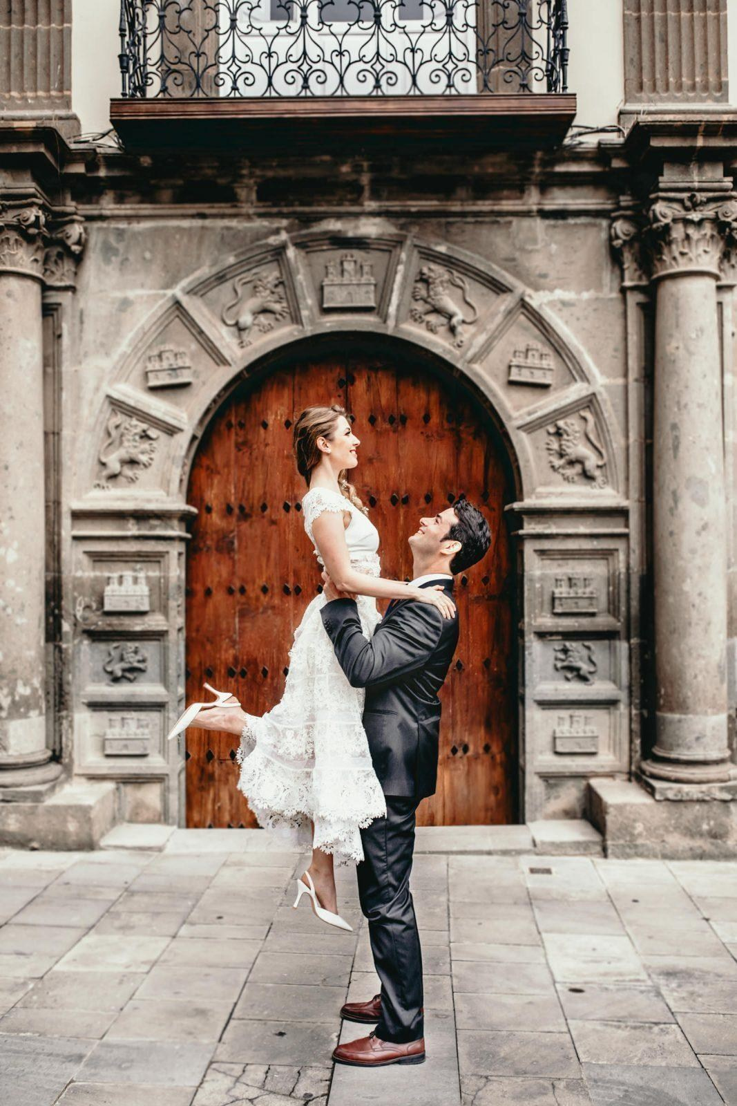 A bride and groom hugging in front of an old door.