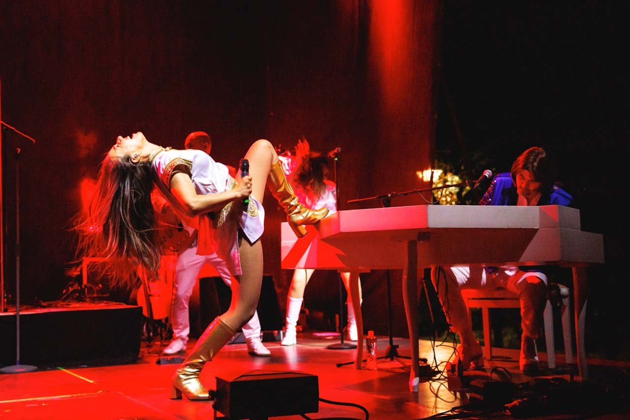 Momenat energičnog plesnog pokretu tokom nastupa na koncertu ABBA Ring Tribute benda u Botaničkoj bašti u Beogradu.