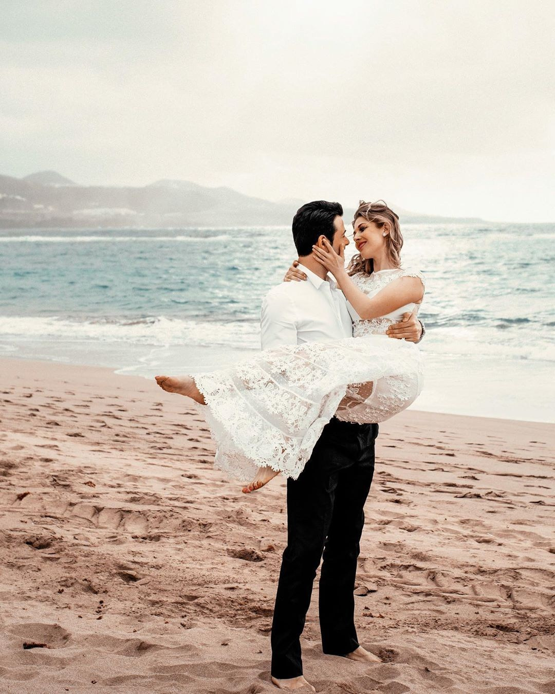 A bride and groom hugging on the beach during their elopement.