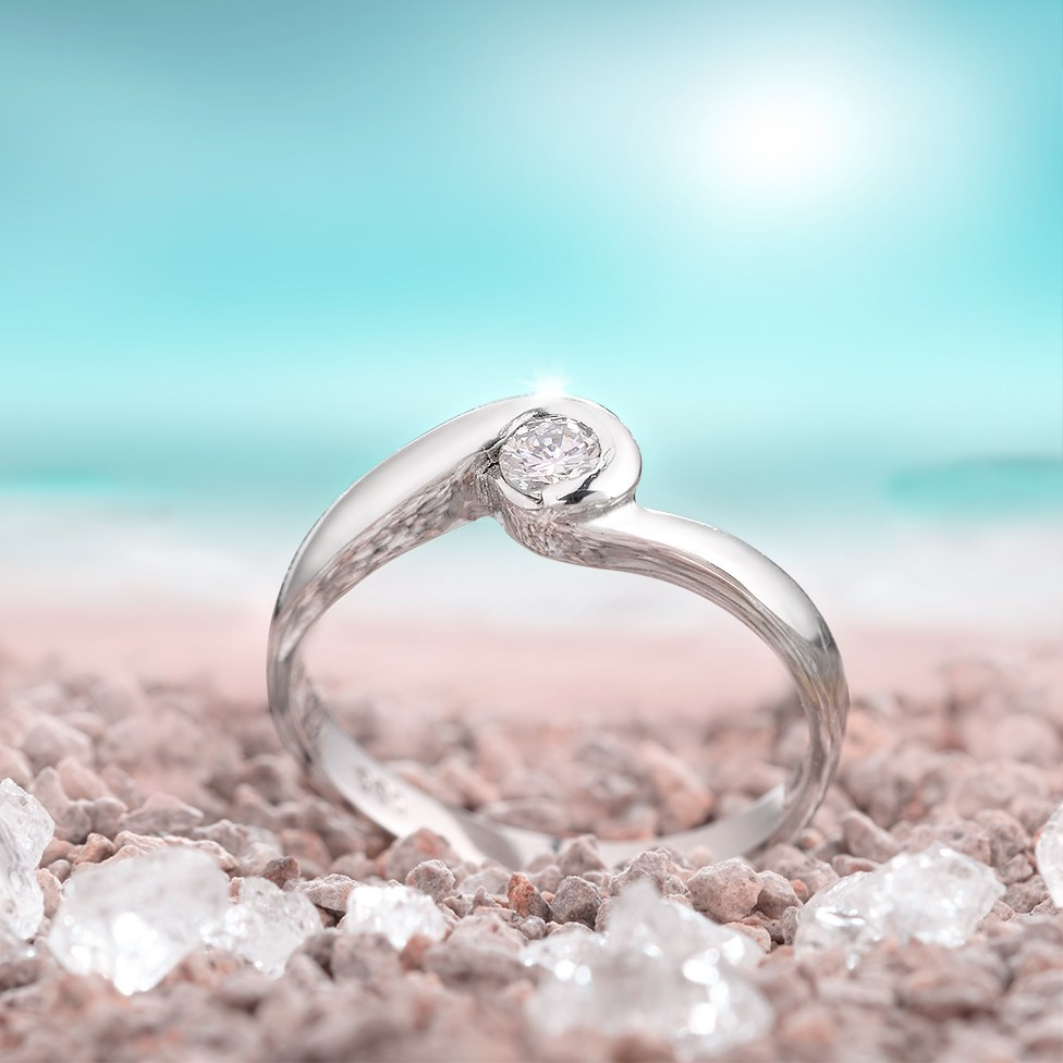 Zlatni prsten na plaži i suncem u pozadini.