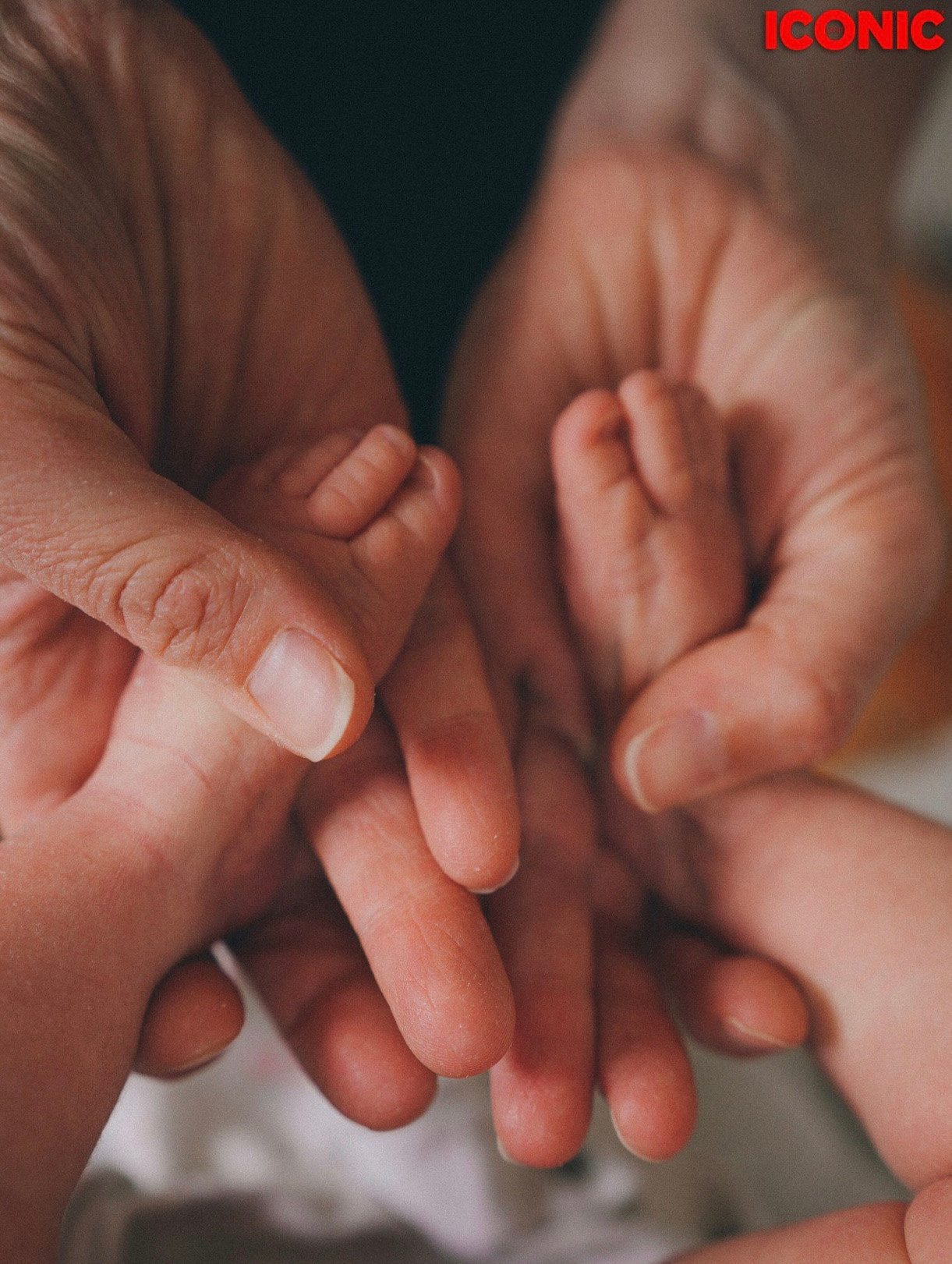 Mum is holding her baby's feet in ICONIC magazine by Irina Zoteeva. Newborn photographer Solihull. Natural newborn photography. Solihull Family Photographer. Newborn lifestyle home photography. Newborn photography near me.