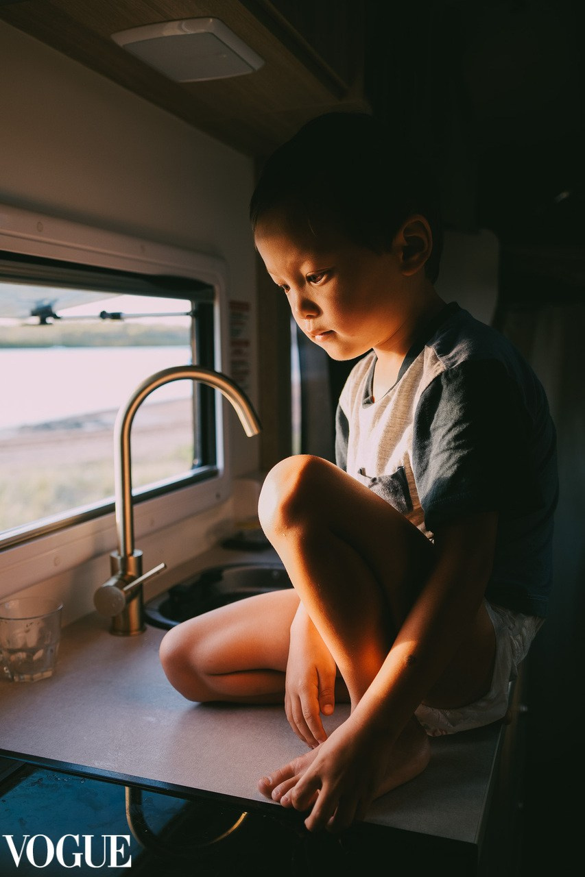 Kids photography by Irina Zoteeva. A boy sitting in motorhome by the window.