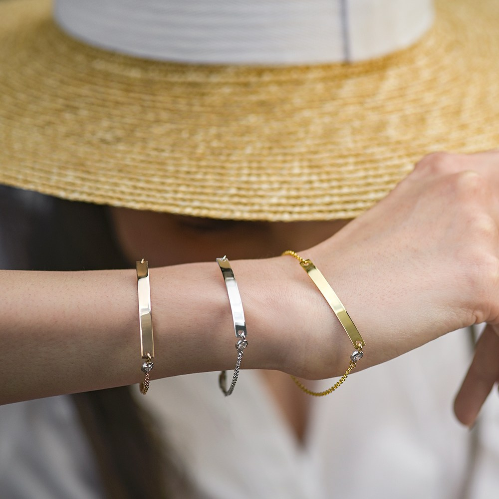 Zlatne narukvice sa pločicom na ruci devojke.