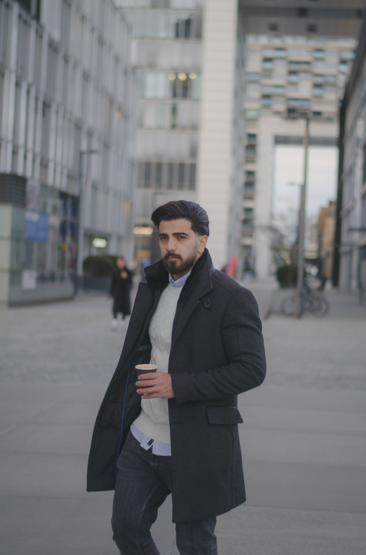 Porträt eines jungen Mannes mit schwarzen Haaren und Bart vor einem urbanen Hintergrund