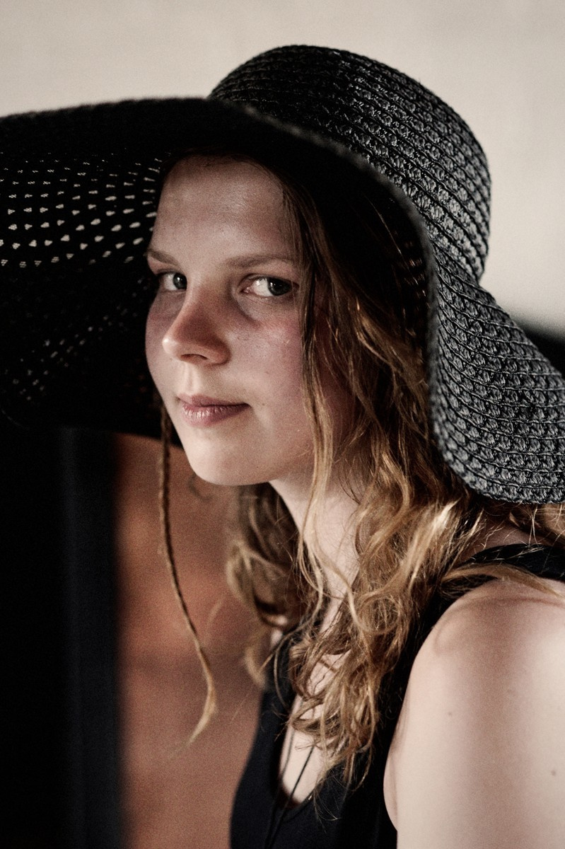 Portrait of a girl with curls in a black hat and black T-shirt.