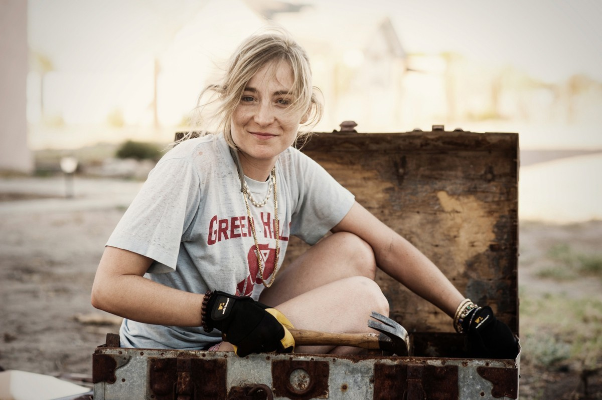 Photo of a young girl student sitting in a trunk during a project at the art summer school.